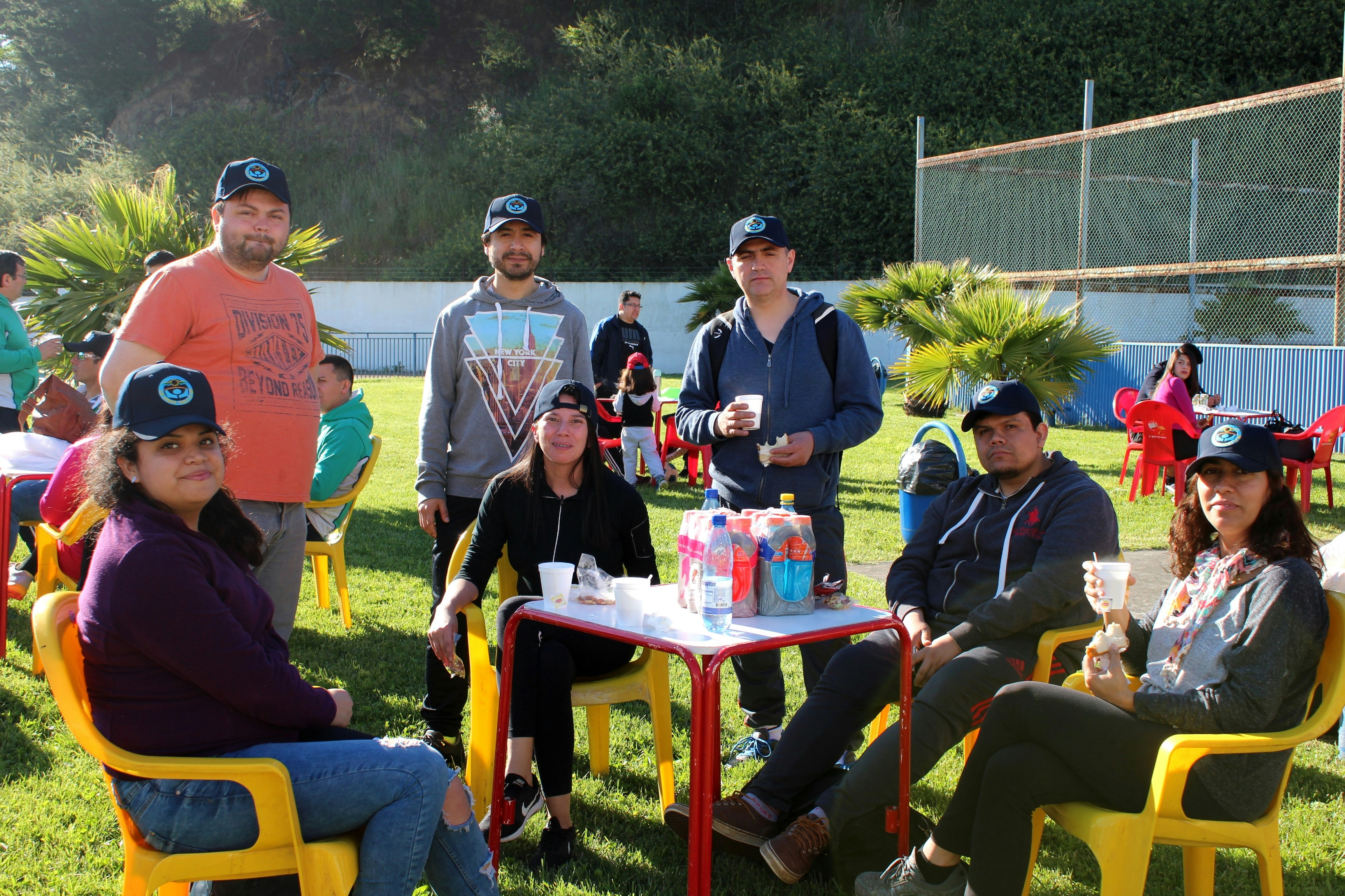 A group of adults wearing matching caps at a table on a sunny lawn, illustrating Annual Content Calendar for 2027: AI Search and Festivals