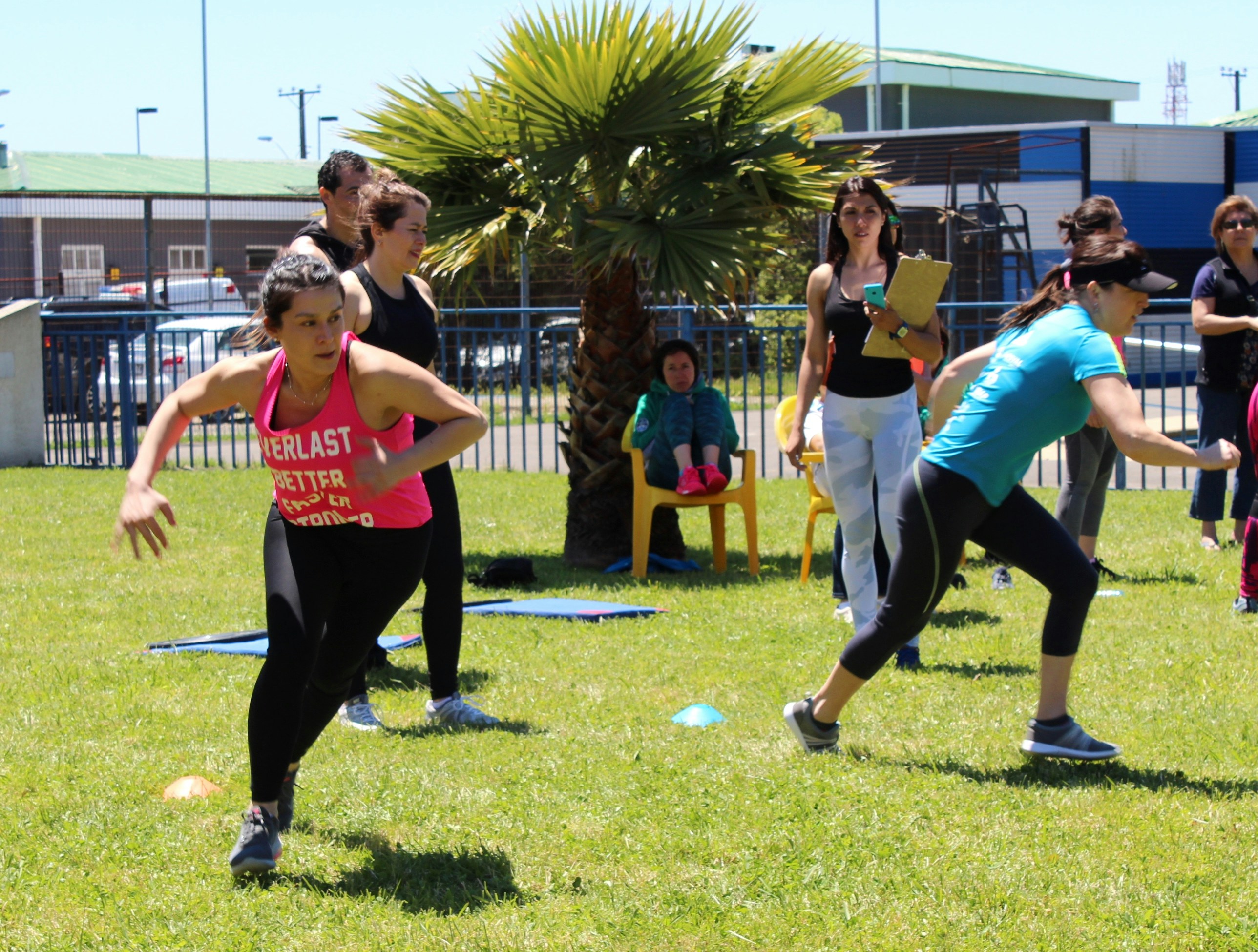 A group of people exercising on a grassy field during an outdoor workout