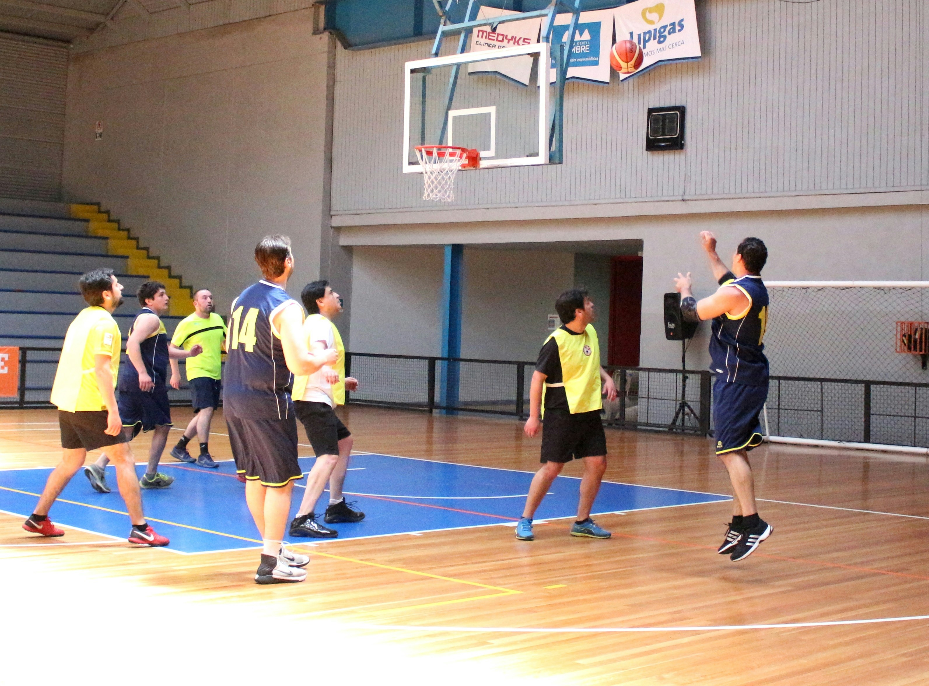 A group of men playing a basketball game on an indoor wooden court