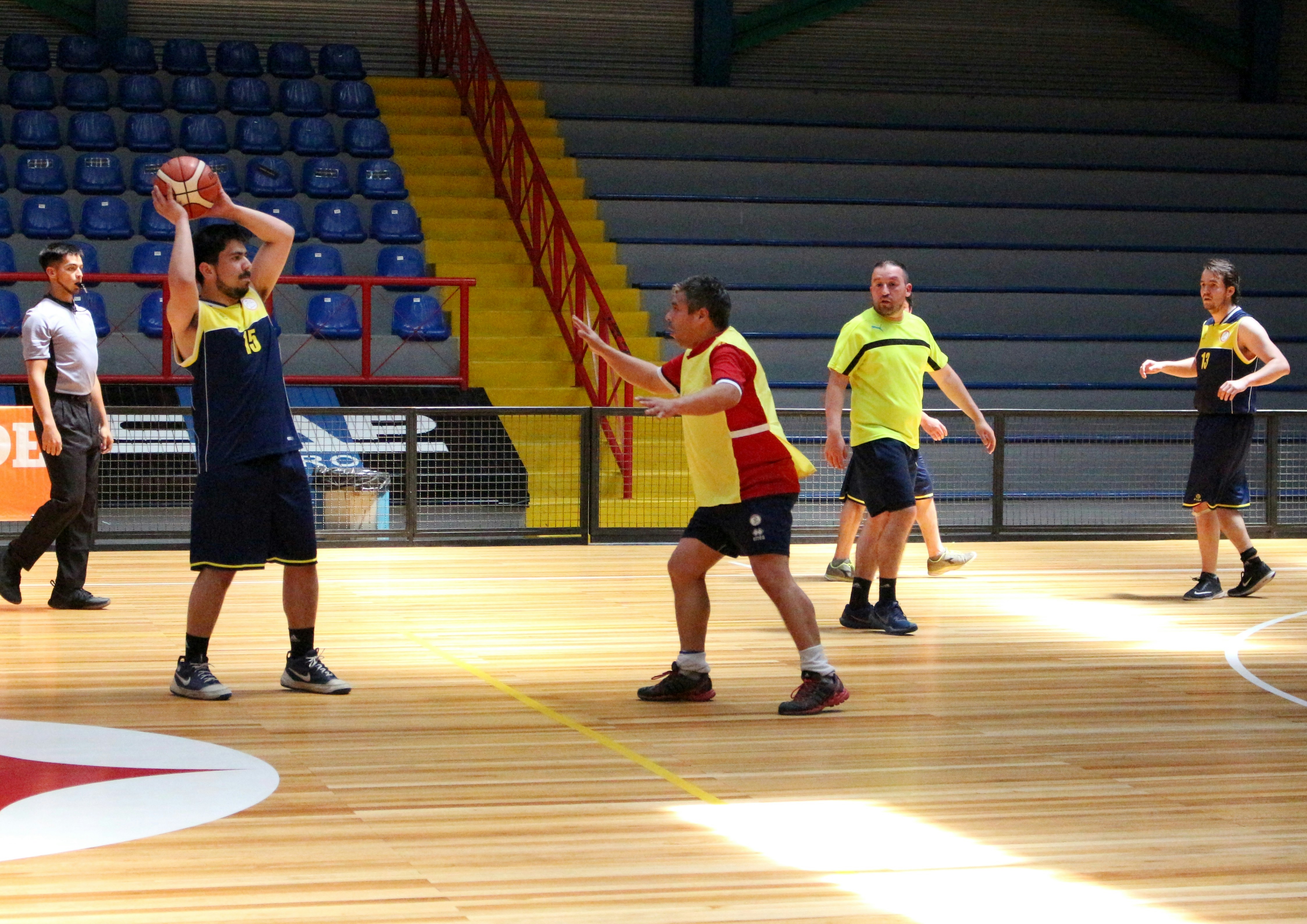 A group of men playing basketball on a wooden court in an arena