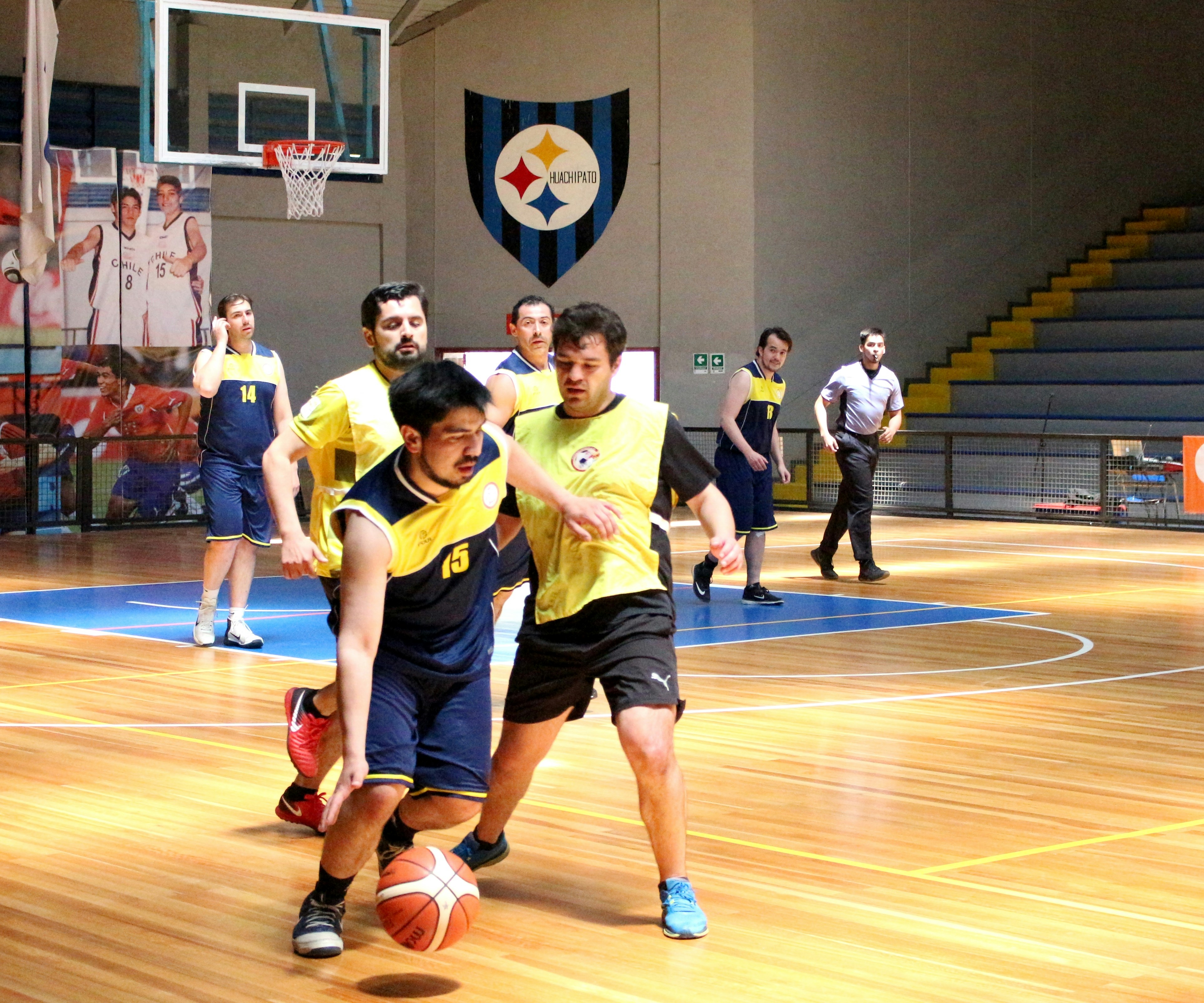 A basketball player dribbling a ball past a defender on an indoor court