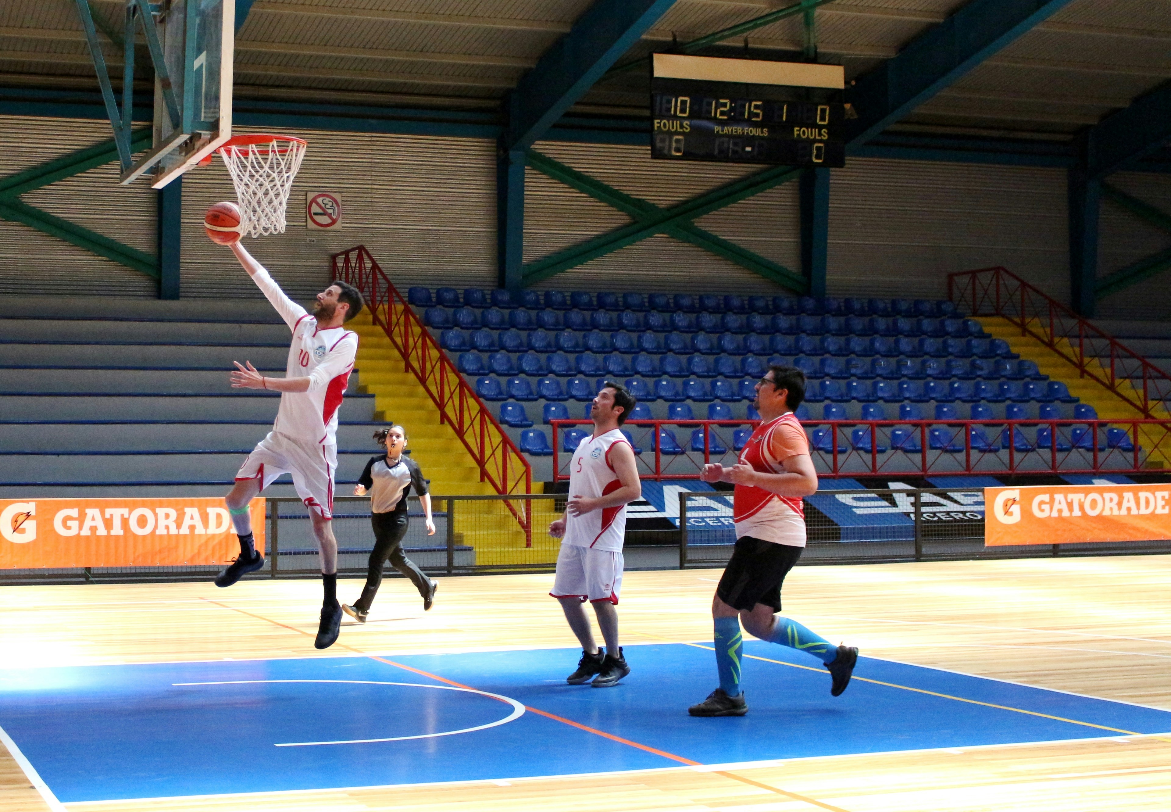 A basketball player jumping to score a basket in an indoor sports arena