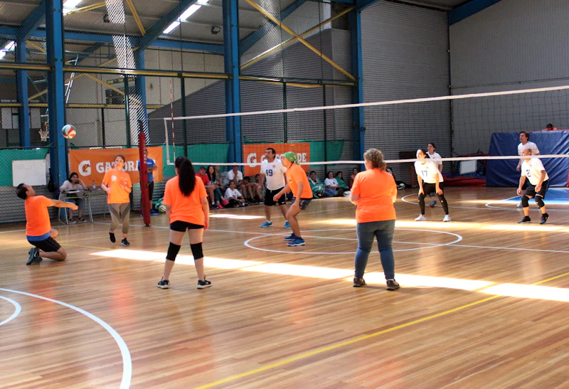 Niñas y niños entrenando vóley en cancha techada