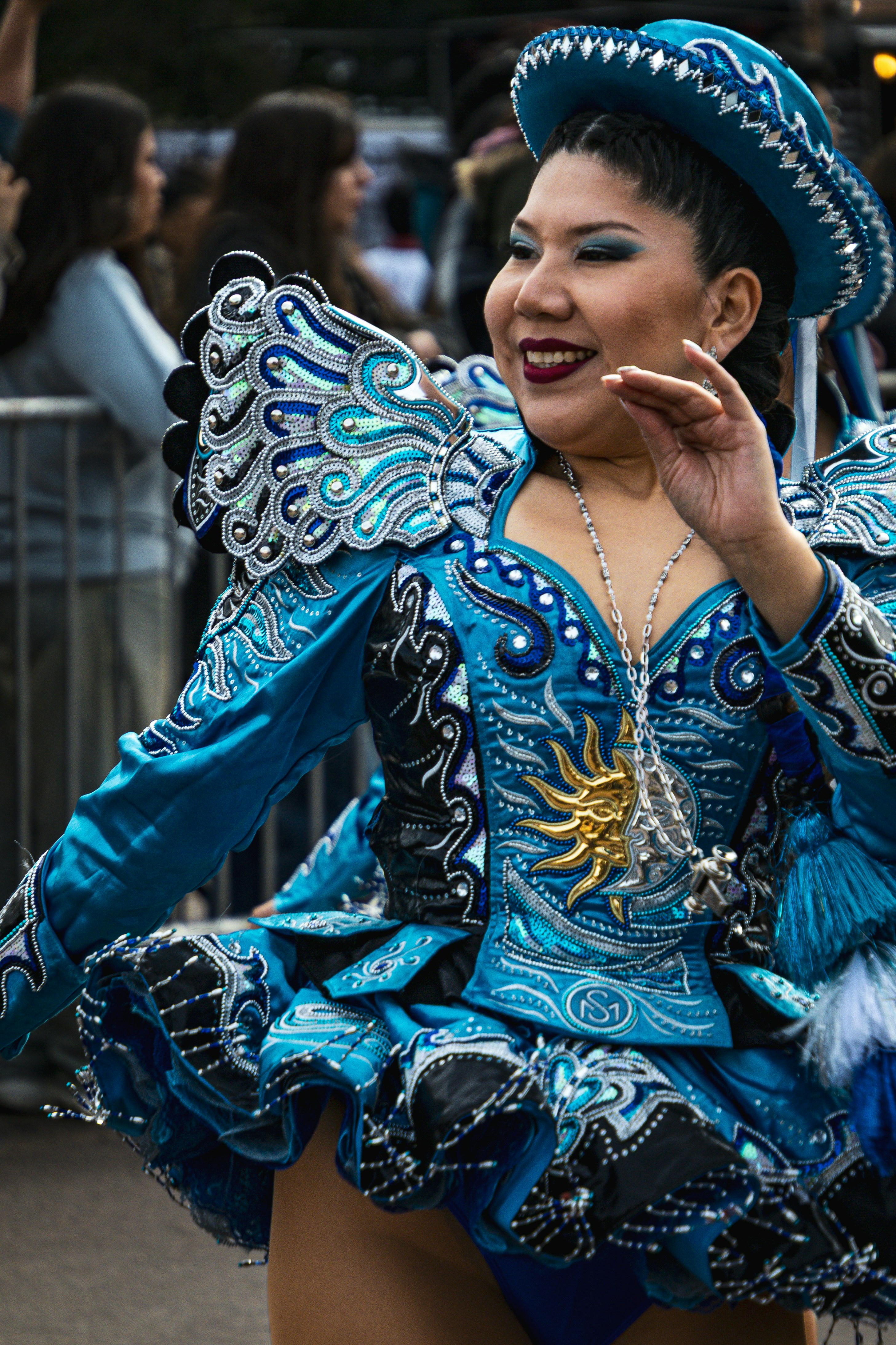 Uma mulher dançando com uma fantasia azul vibrante de lantejoulas e um chapéu combinando.