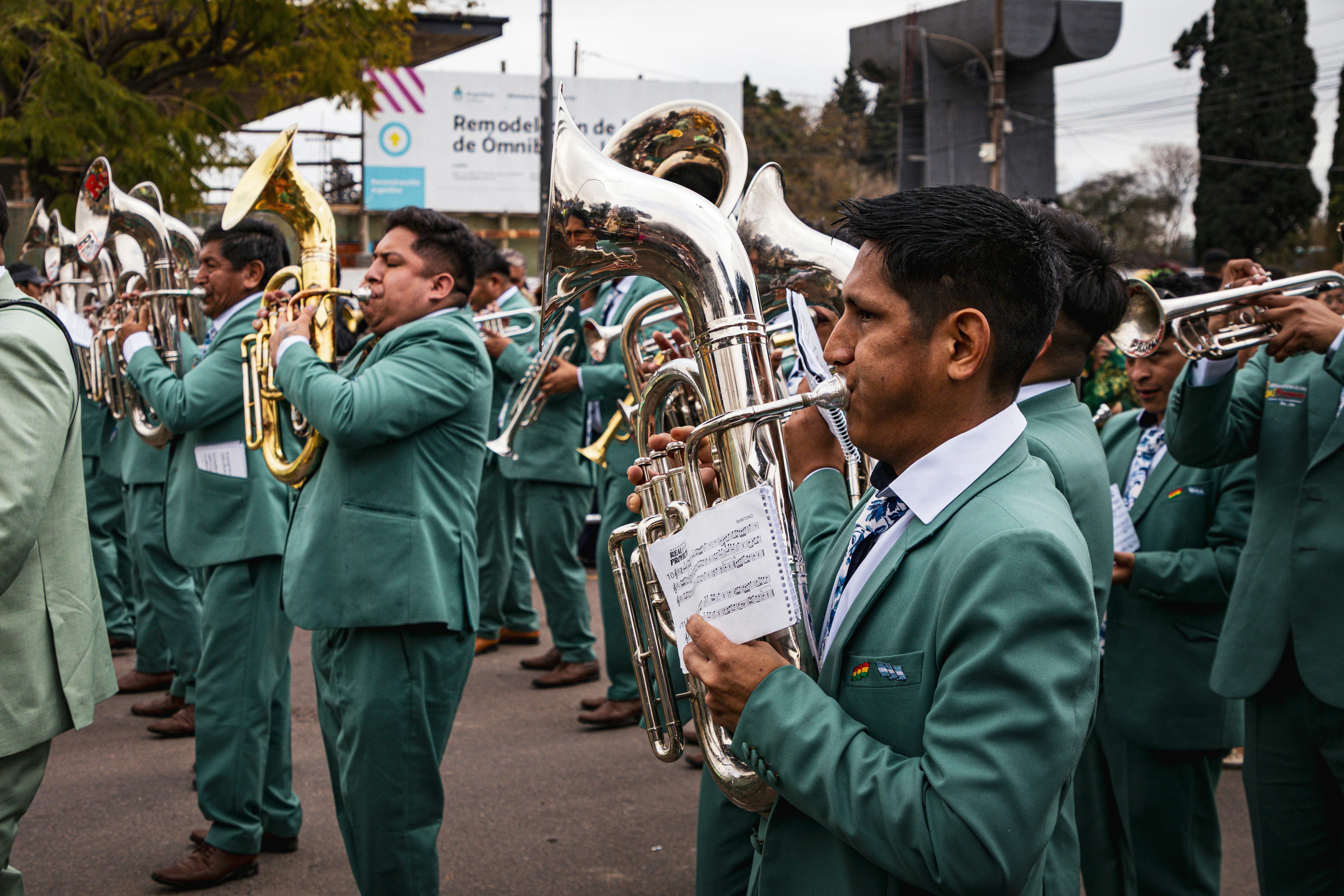Uma banda de metais em ternos verdes combinando tocando instrumentos em uma rua da cidade.