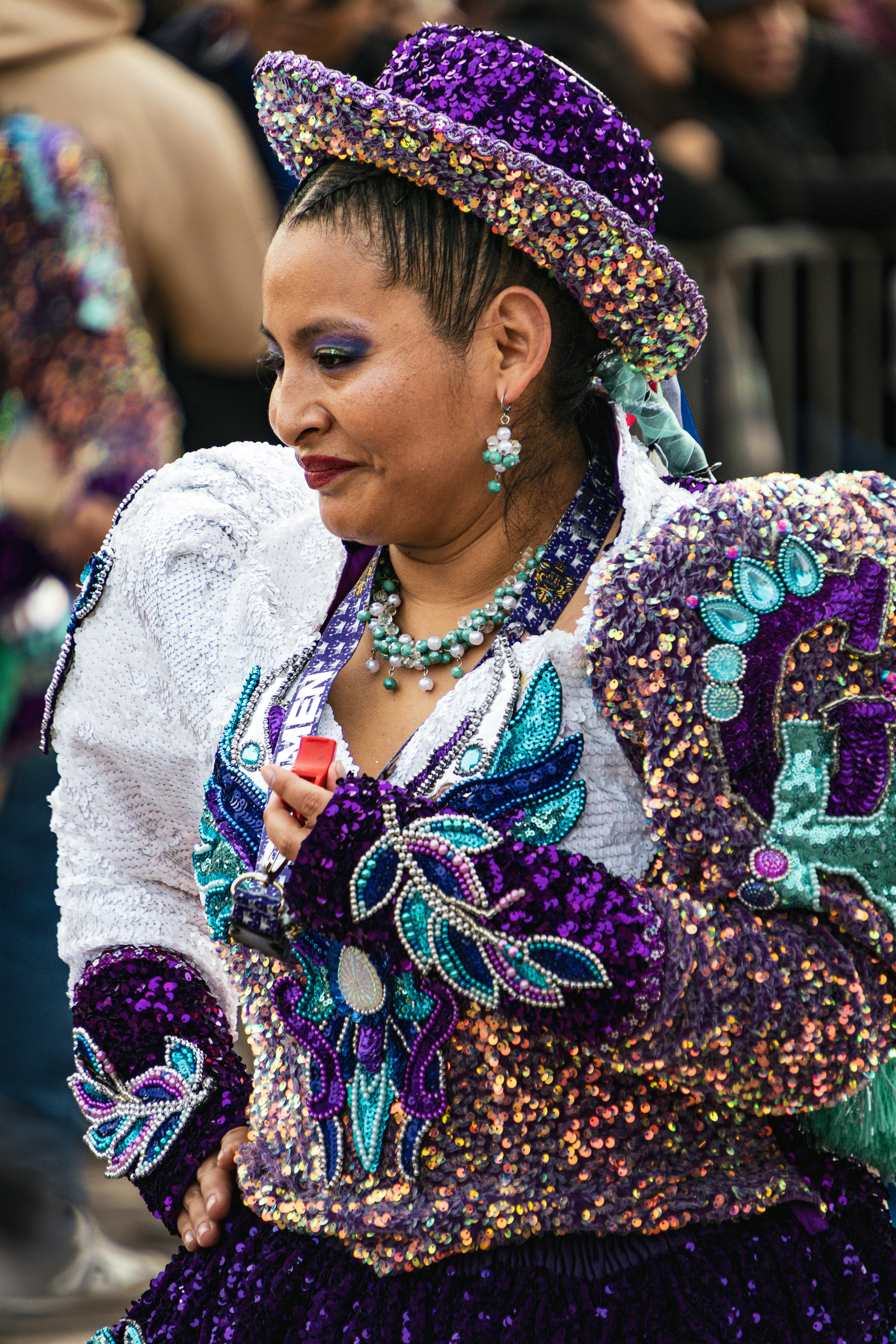 Uma mulher com um traje roxo e branco com lantejoulas, com um chapéu combinando.