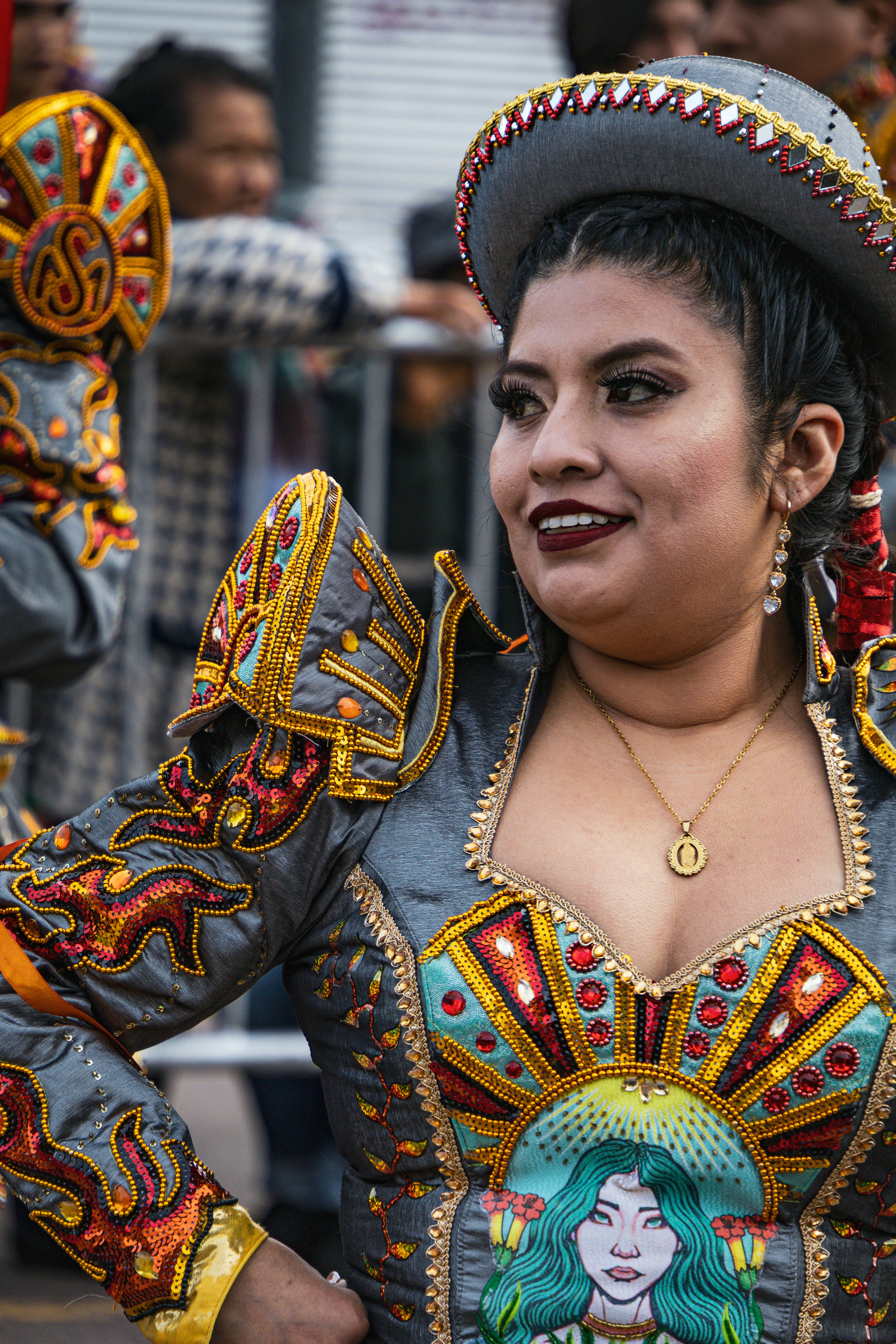 Uma mulher com um traje cinza e dourado com lantejoulas, com um chapéu combinando.