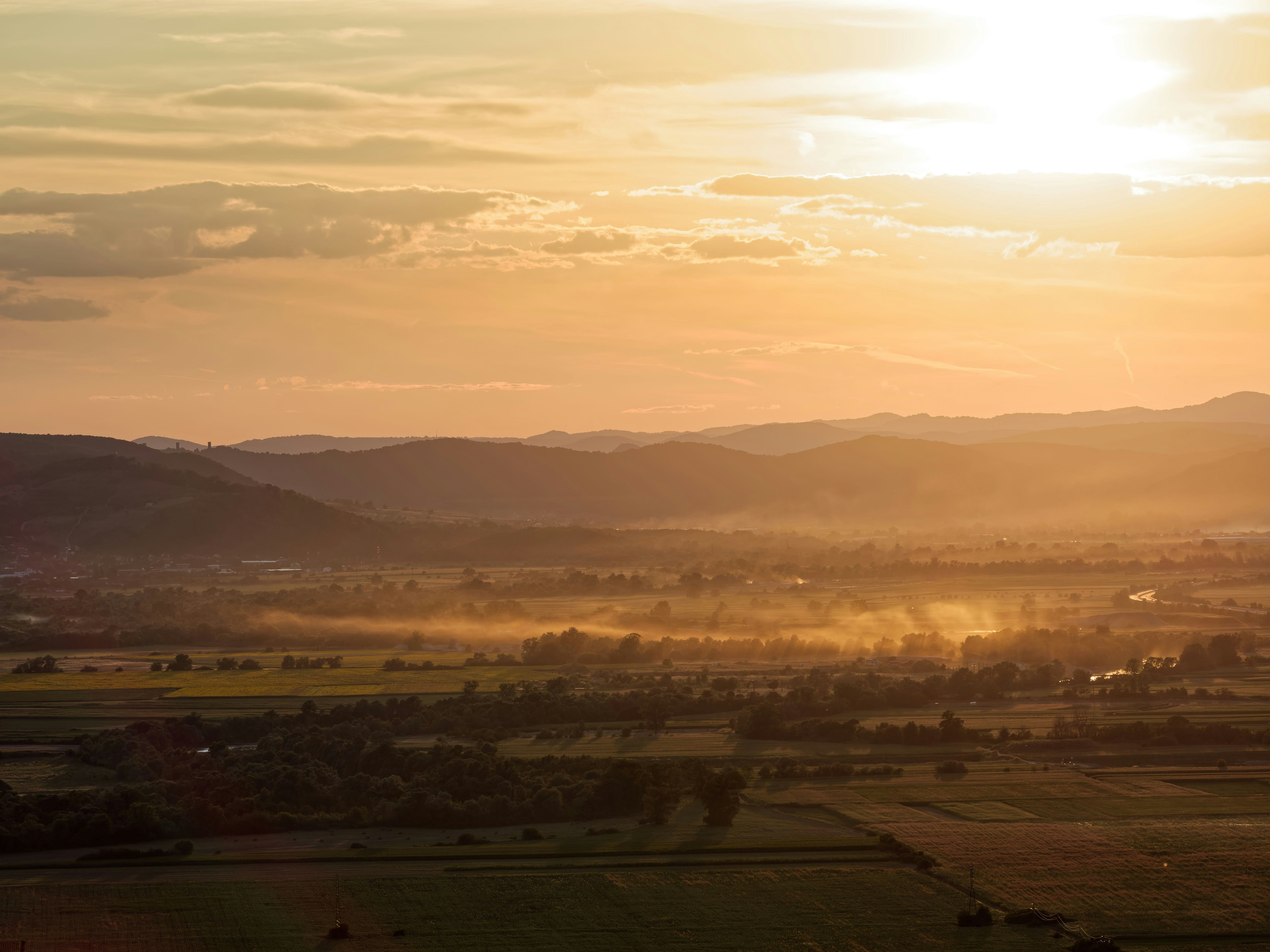 Golden sunset over a misty valley and distant mountains.