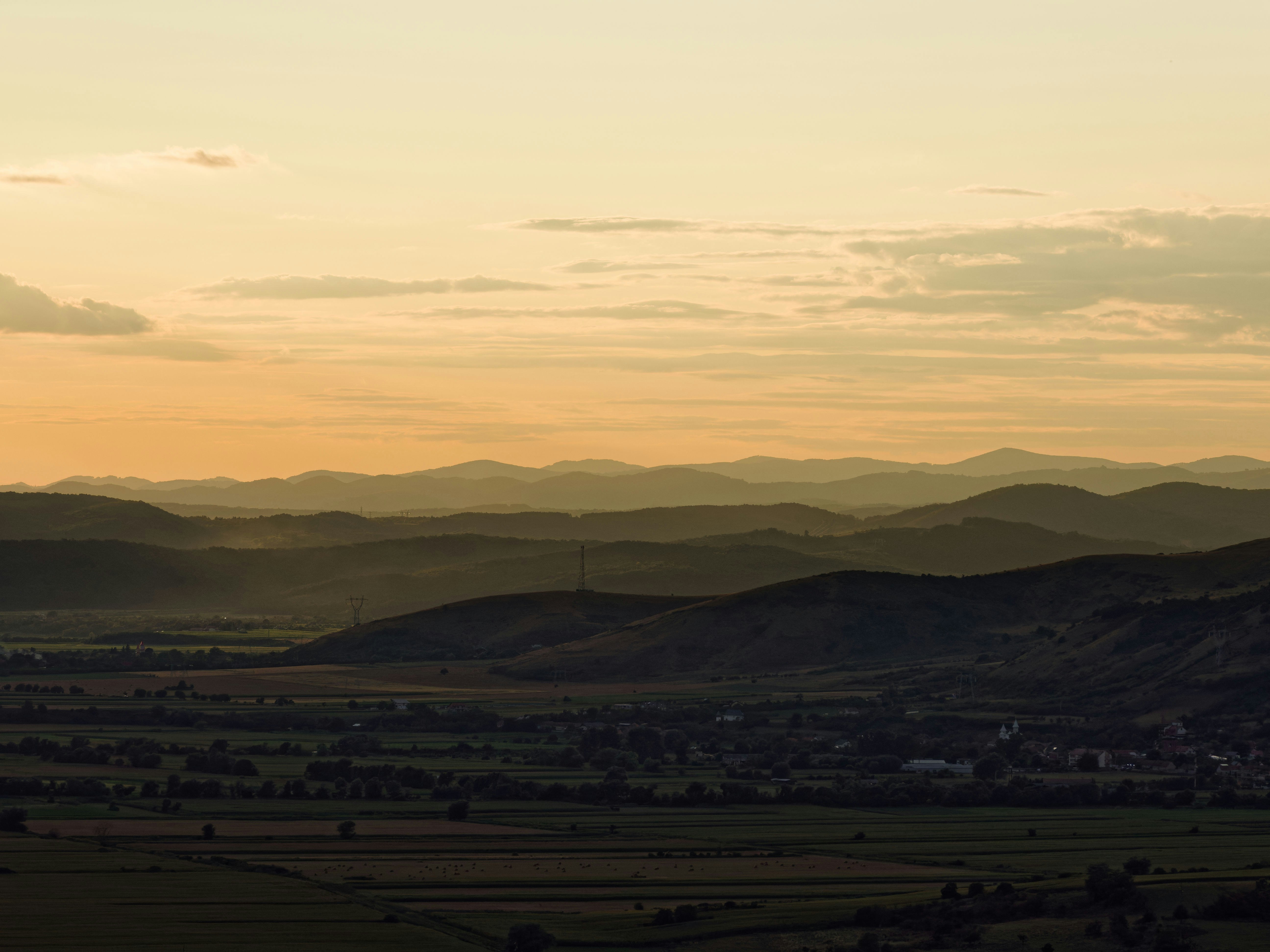 Golden sunset over layered mountains and a valley town.