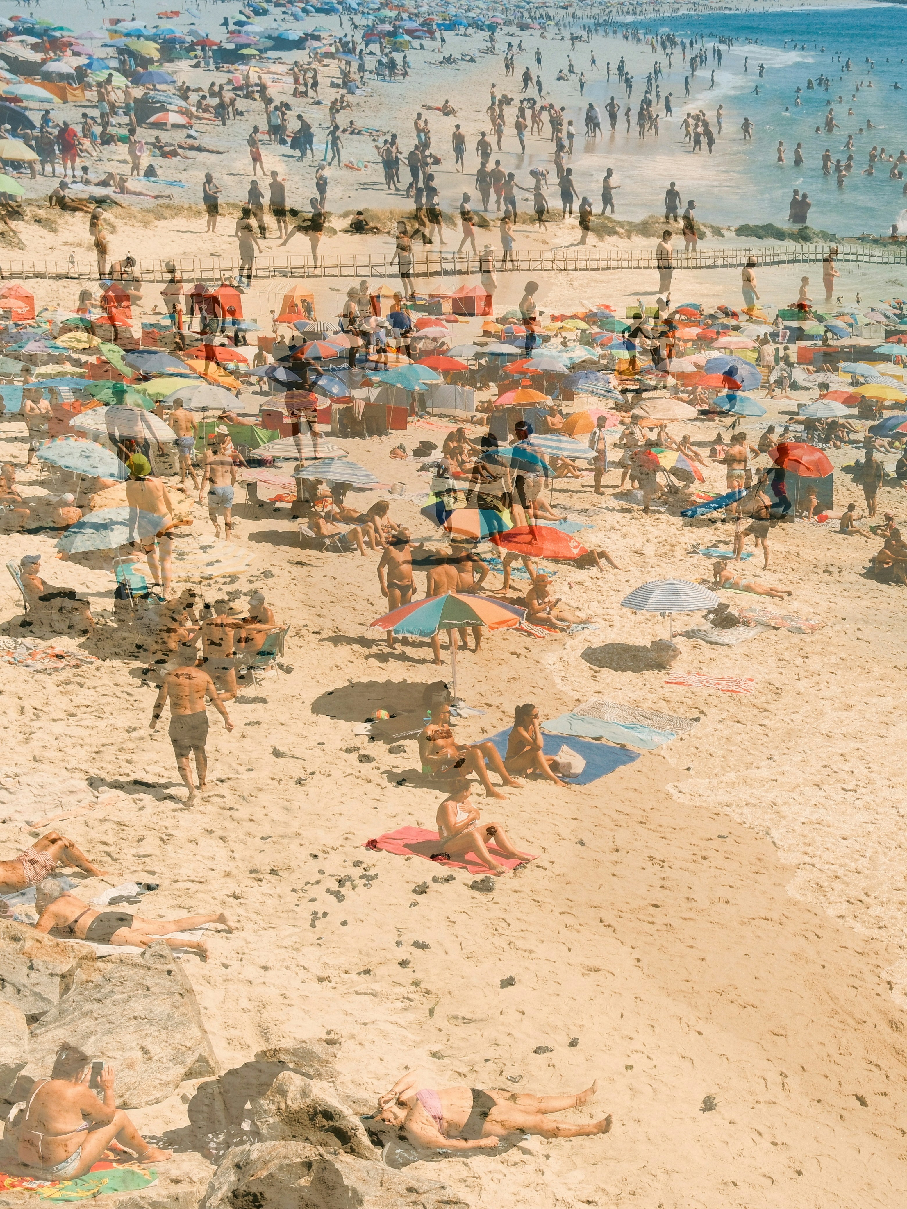 A crowded beach with many people and colorful umbrellas.