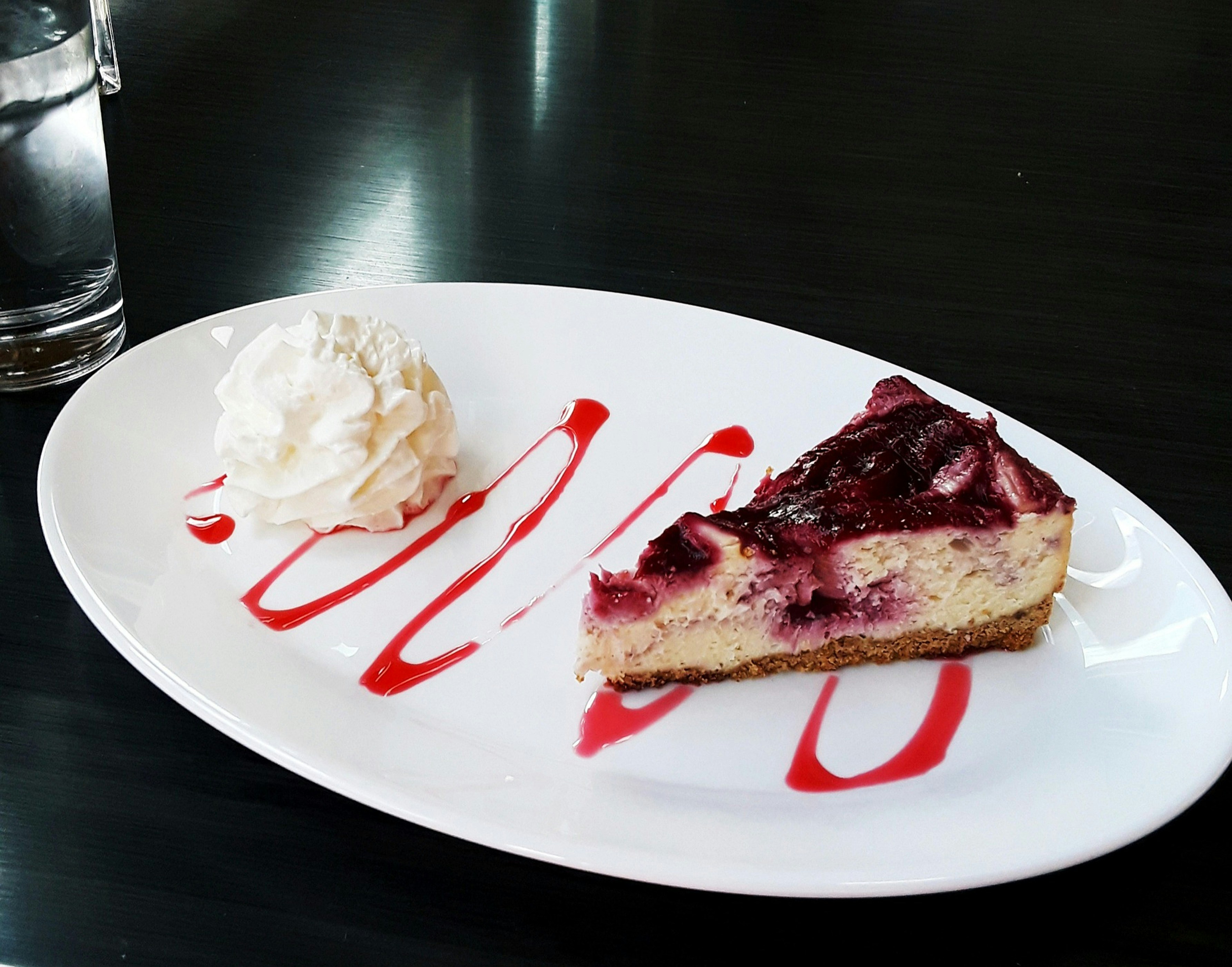 Dessert plate with berry cheesecake, ice cream, and red sauce