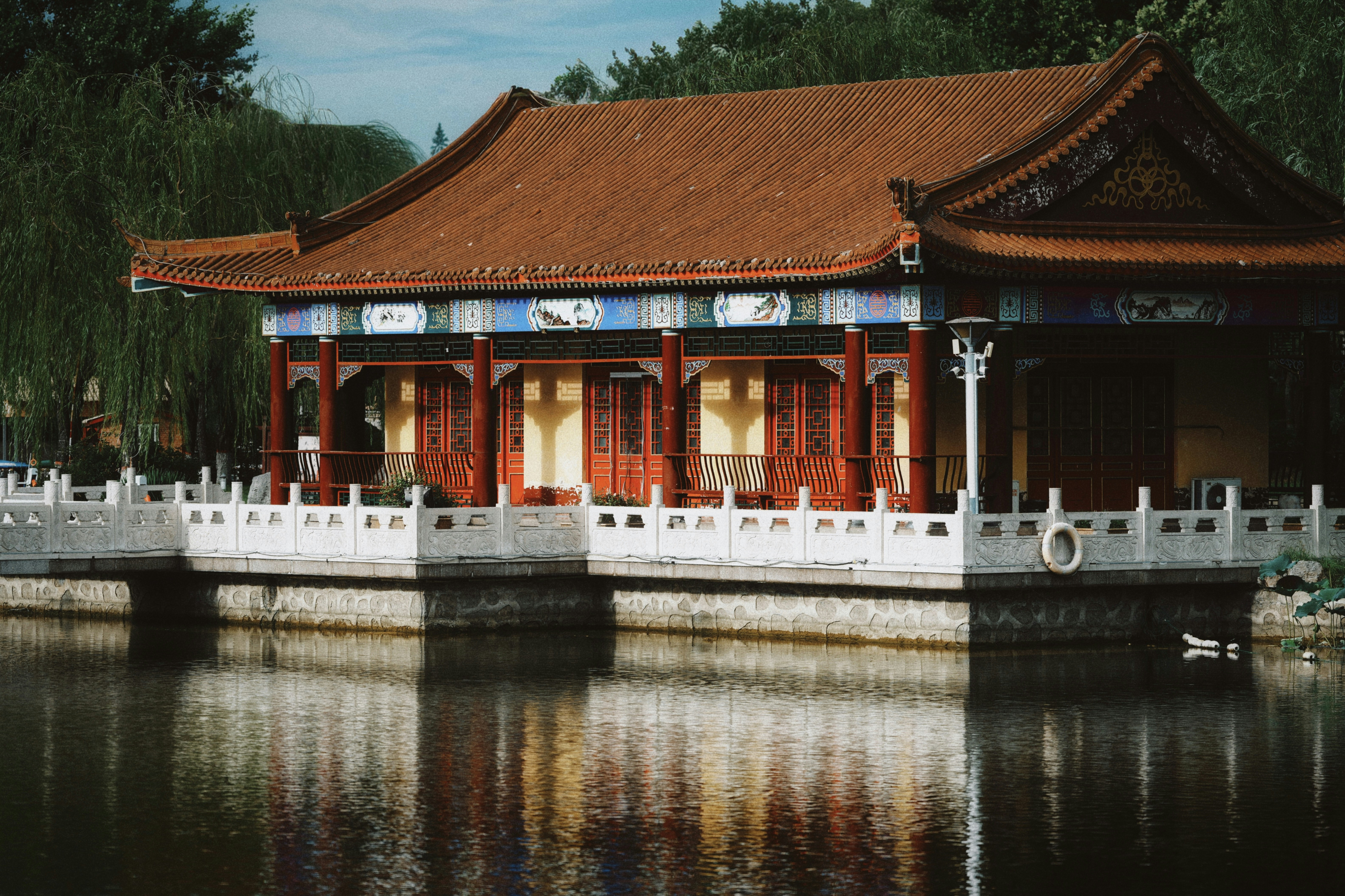 Traditional chinese building with red roof reflected in water