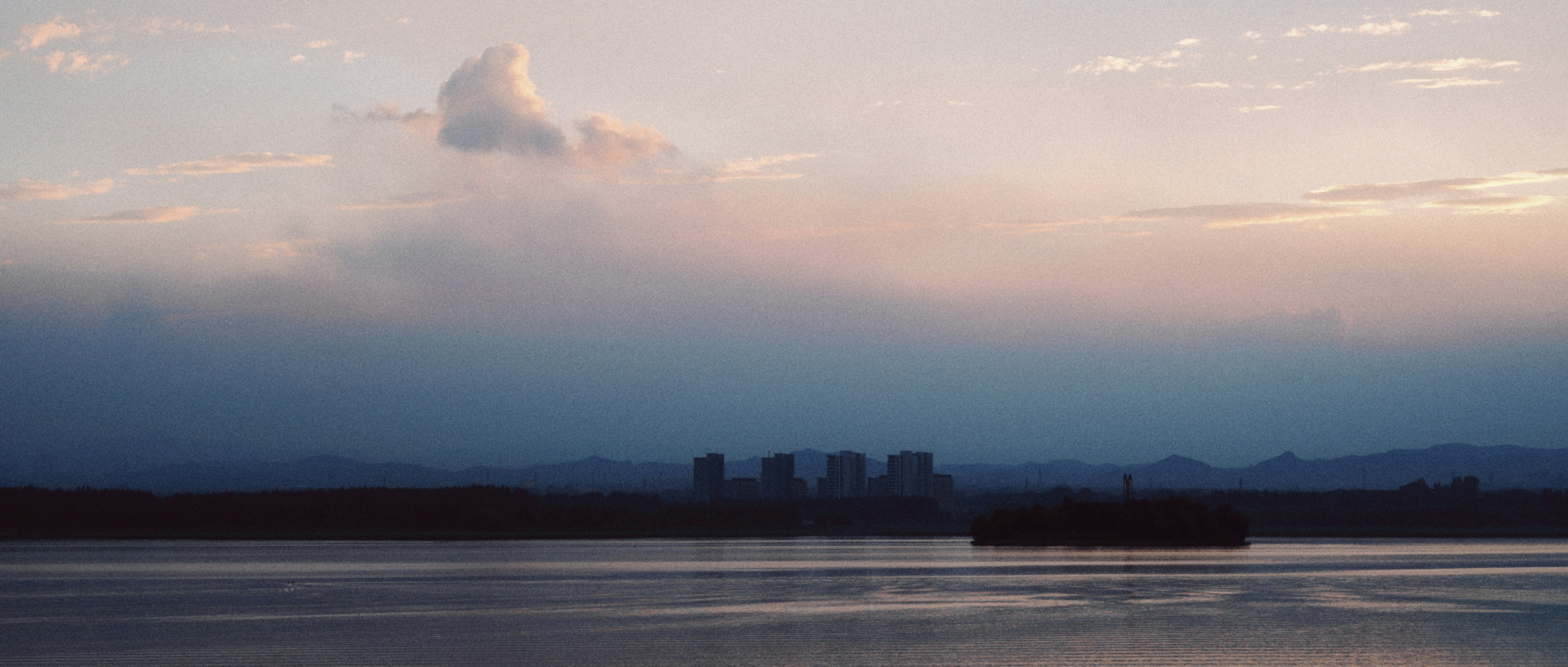Sunset over a lake with distant city silhouettes