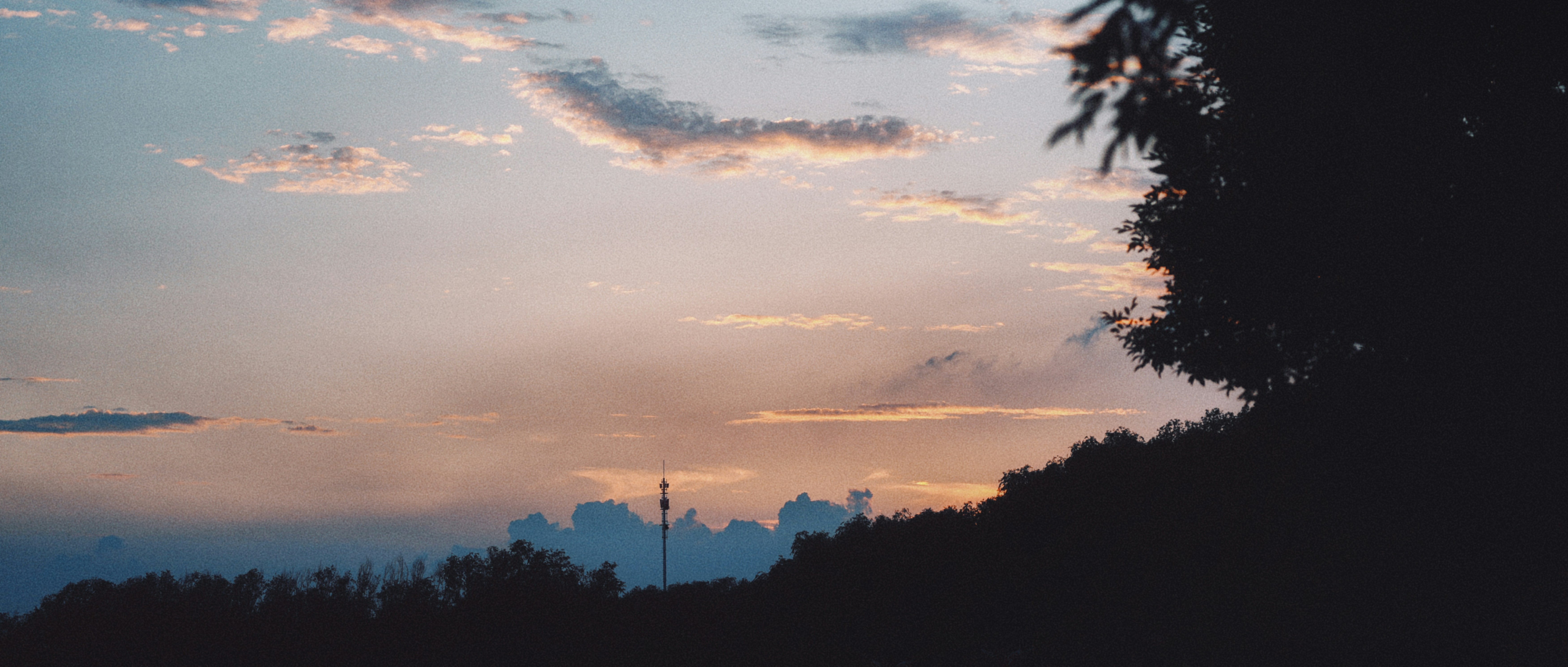 Colorful sunset sky over silhouetted trees and distant structures