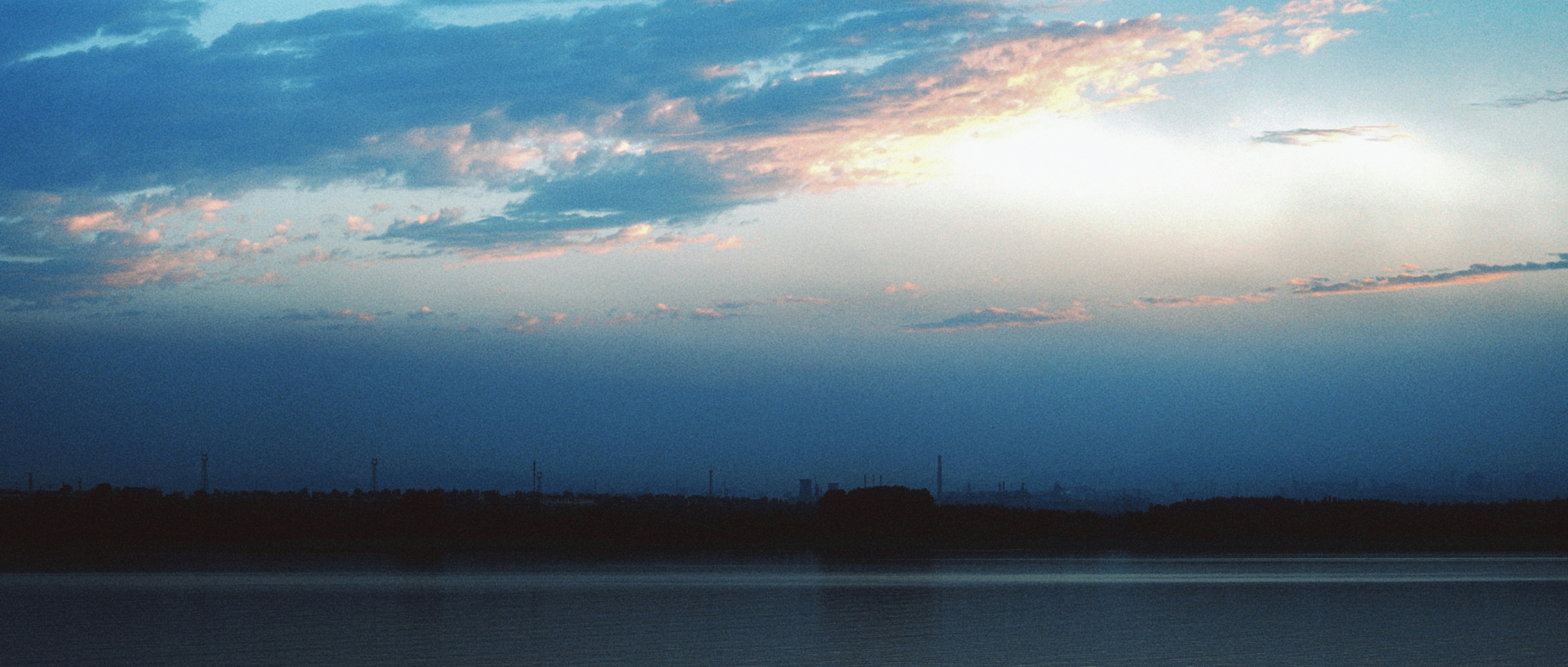 Sunset glow illuminates clouds above tranquil water