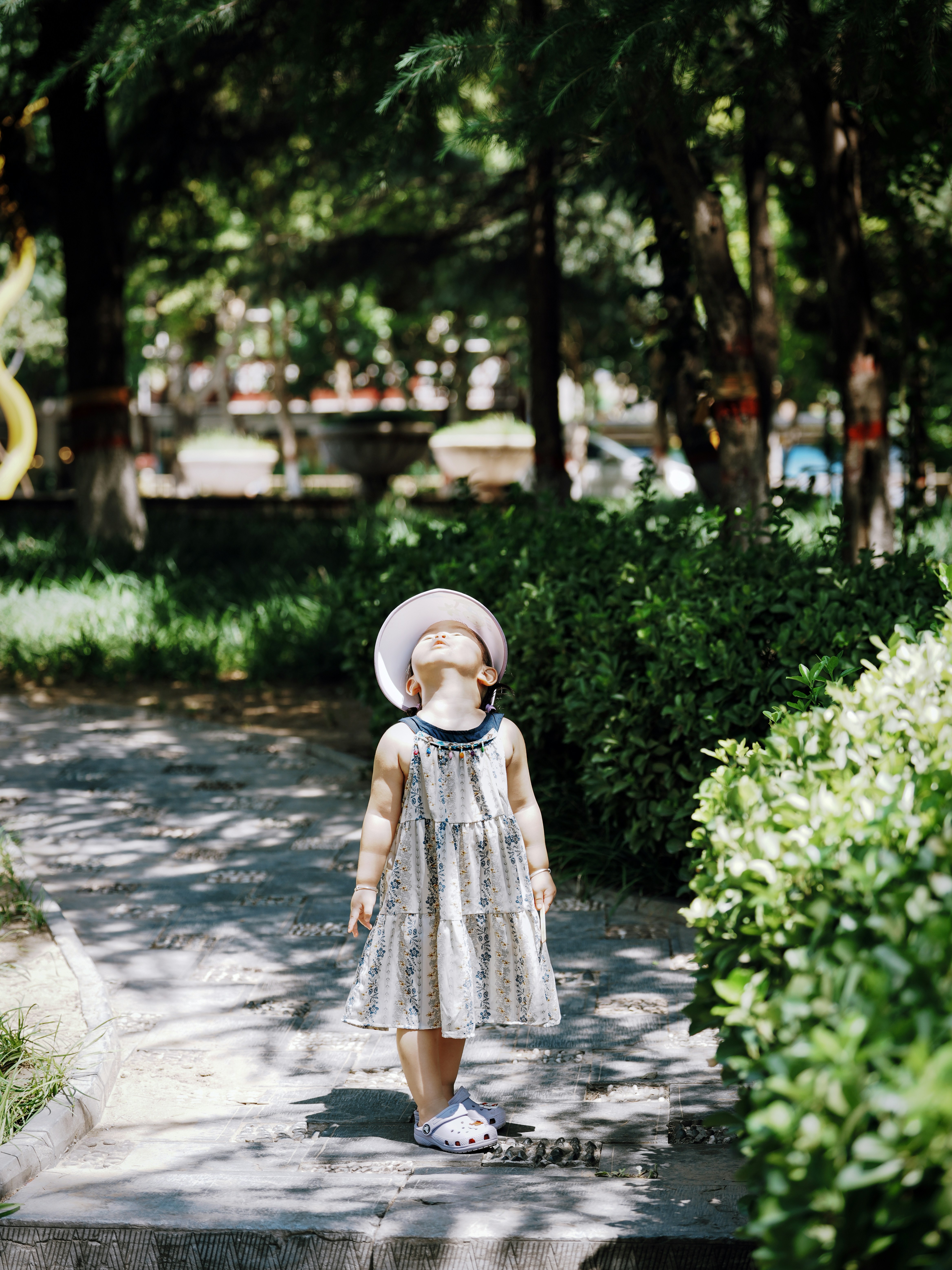 Little girl in a hat looking up outdoors