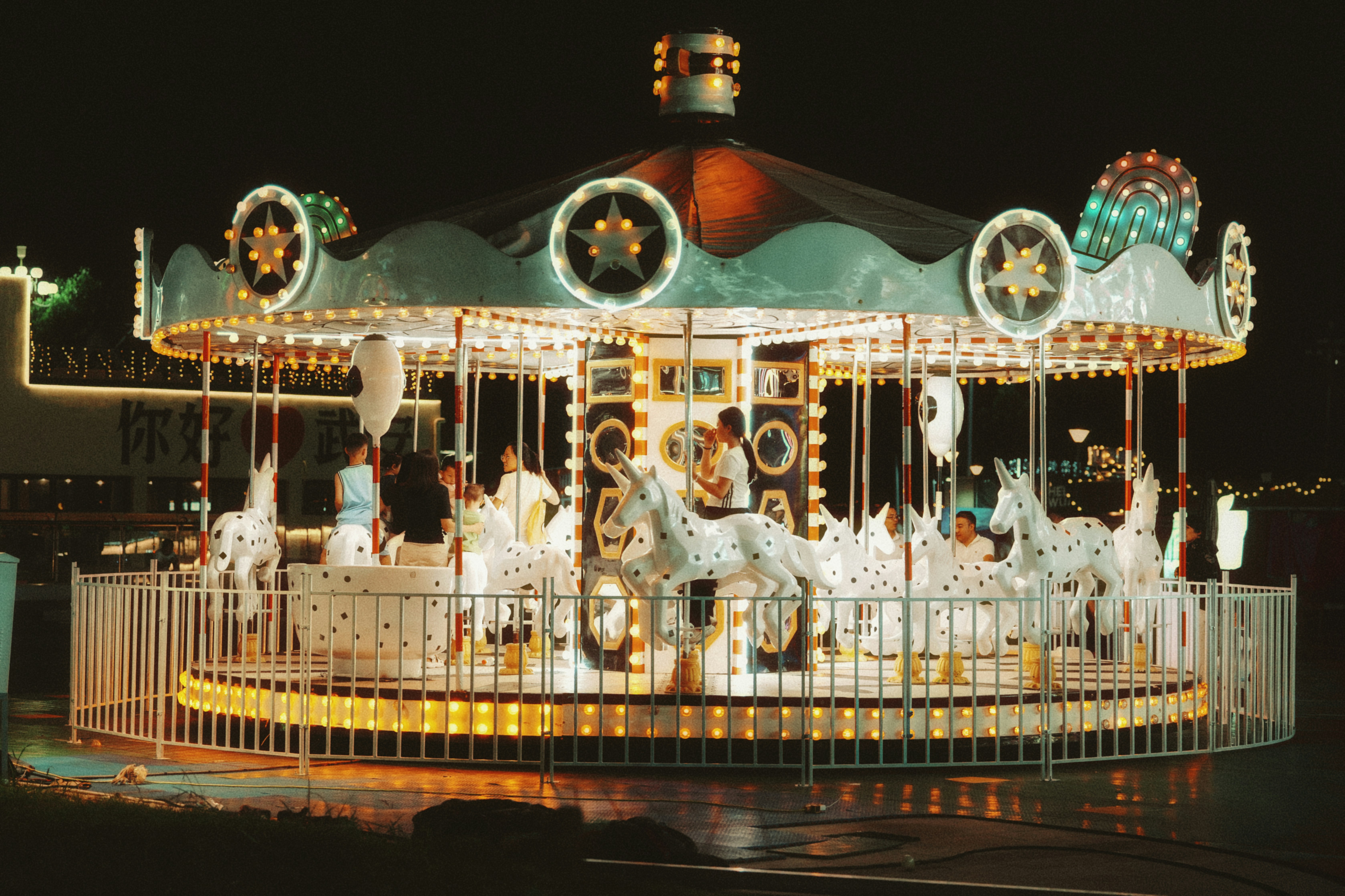 A brightly lit carousel with people riding at night