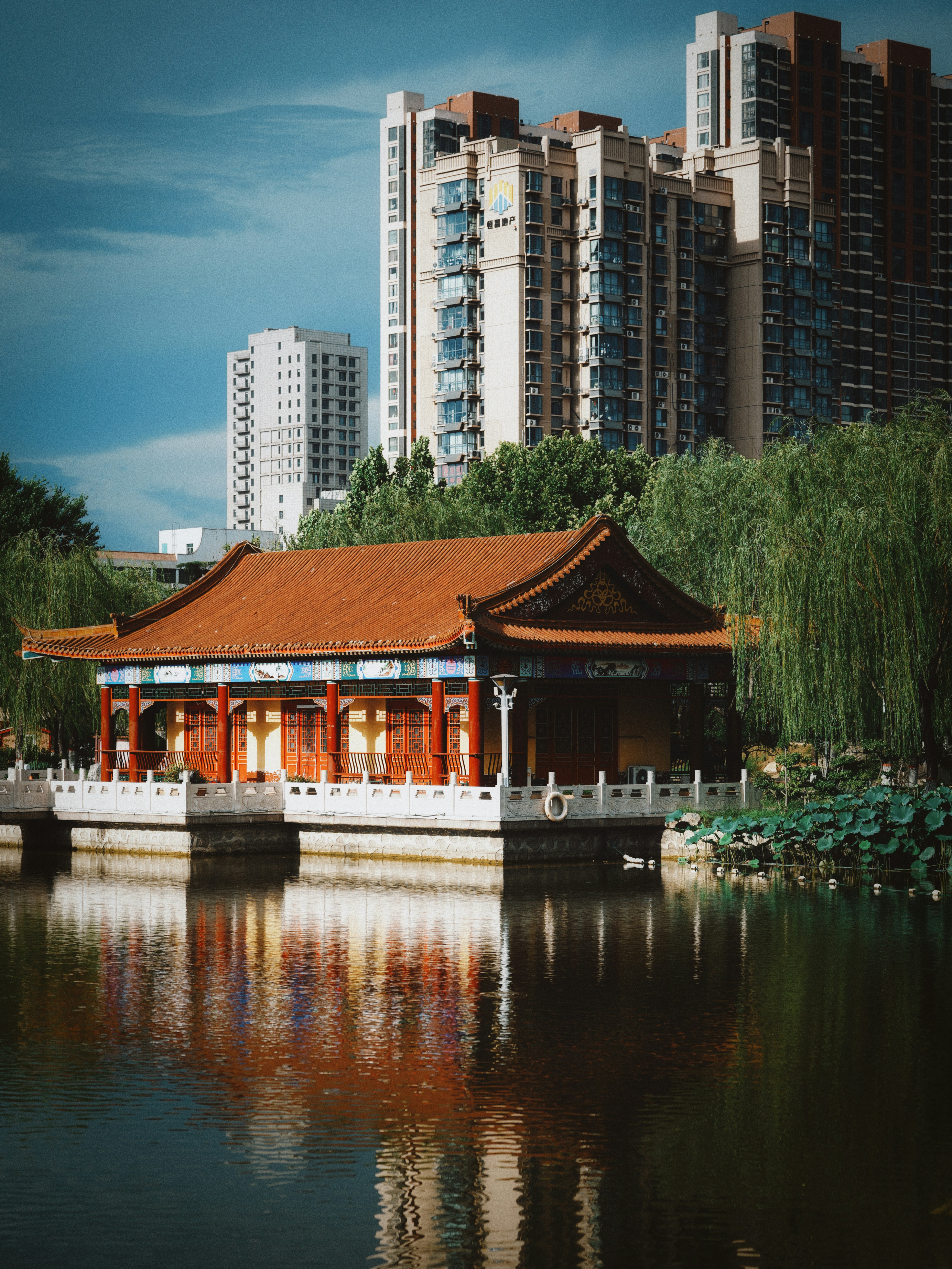 Ancient chinese pavilion on water reflecting modern city buildings