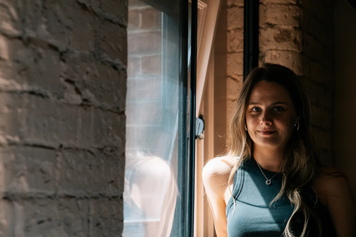 A young woman smiling by a sunlit window