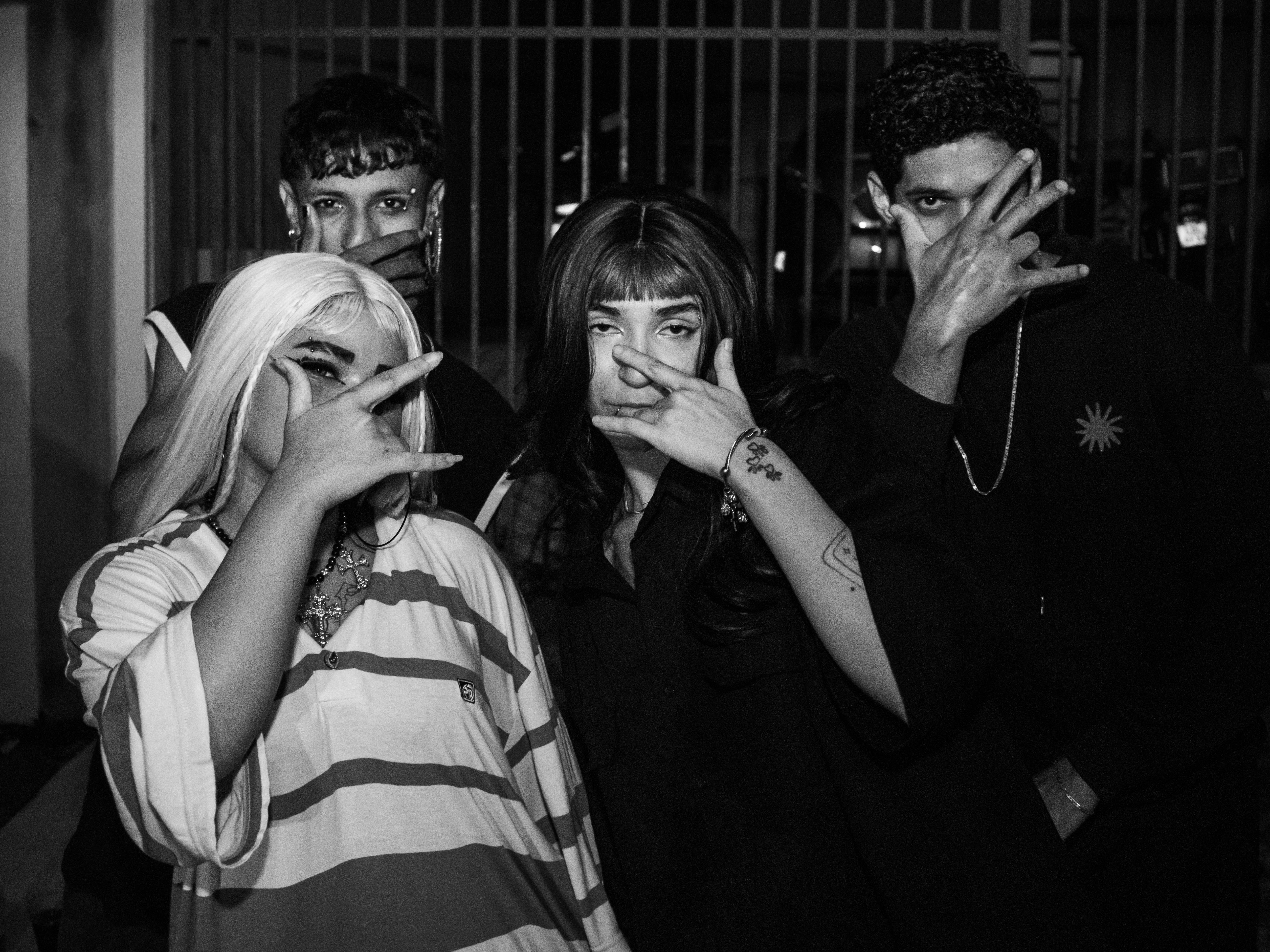 Four people pose with hand gestures in black and white.