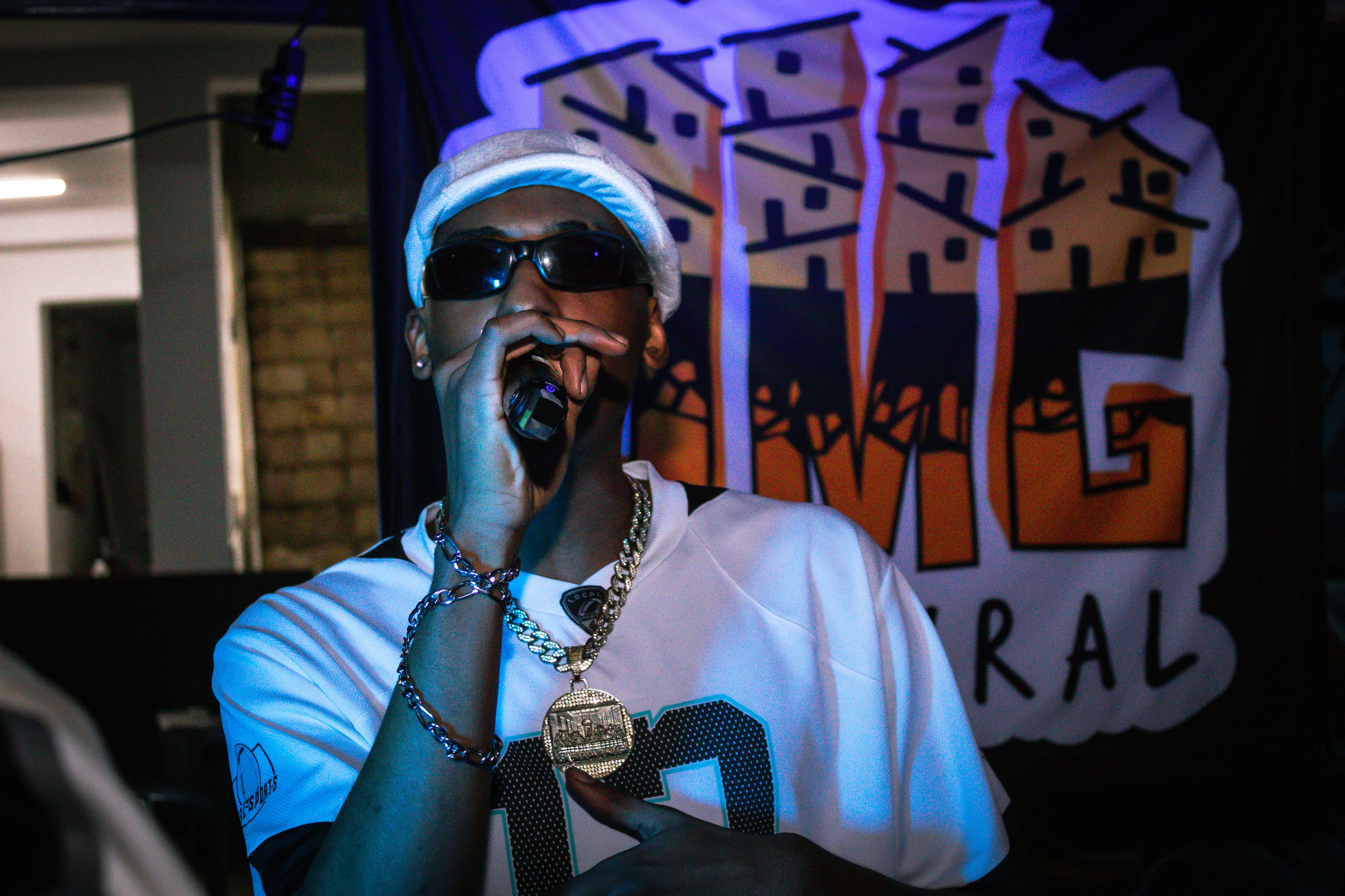 Man in sunglasses and chains performs with microphone
