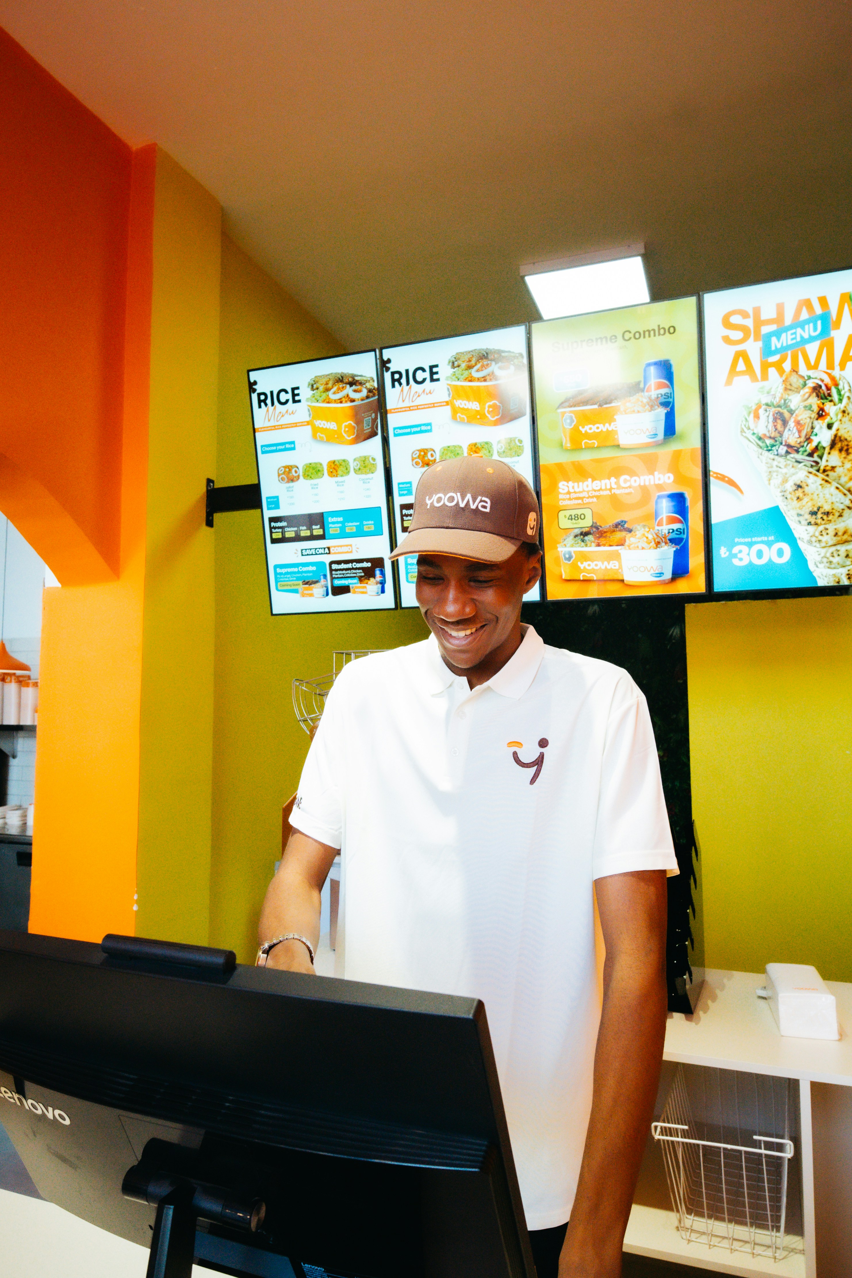 Um homem sorridente de uniforme trabalhando em um balcão de fast-food.