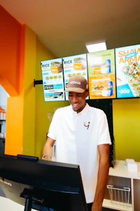 A smiling man in uniform working at a fast-food counter