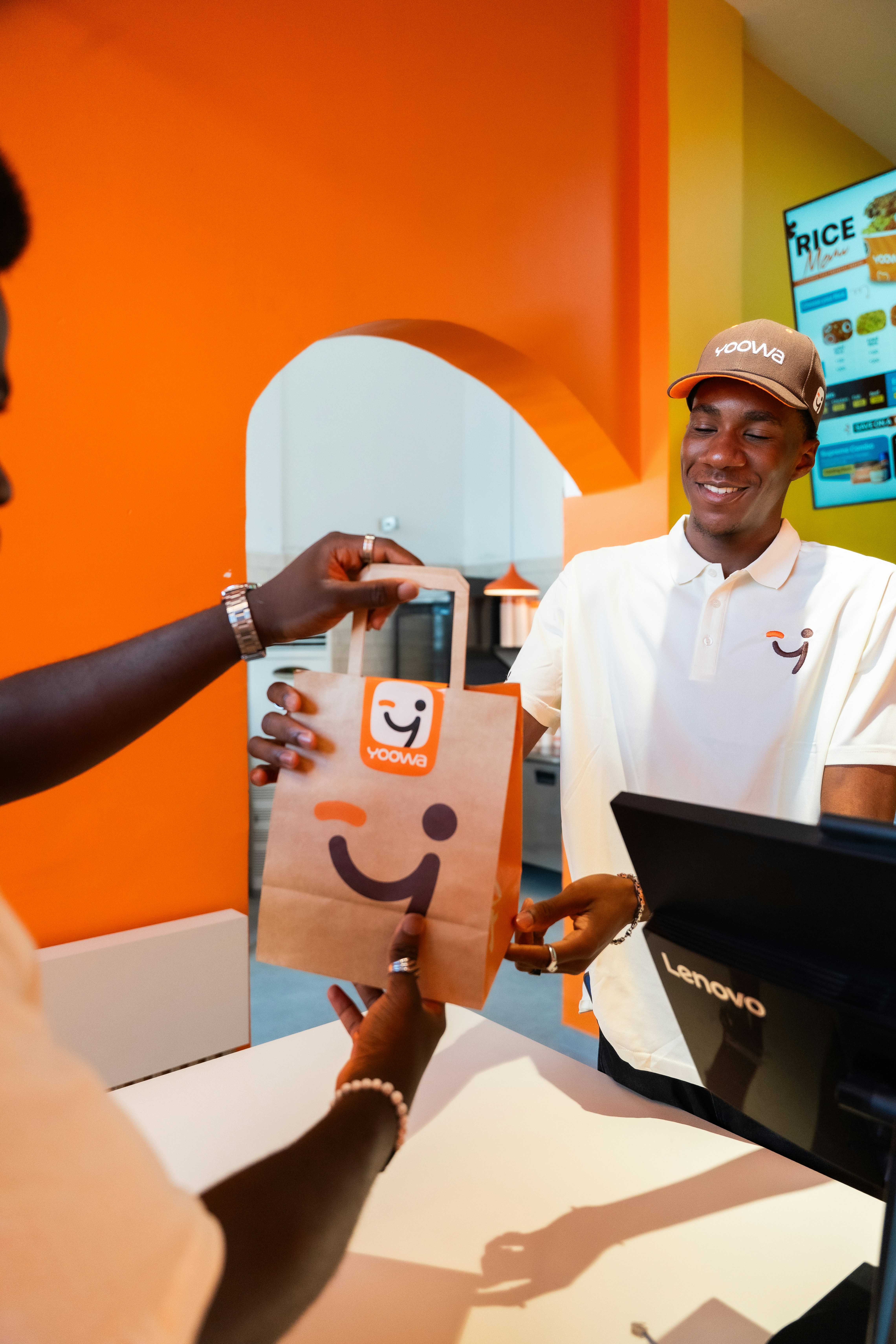 A smiling server hands a branded bag to a customer.