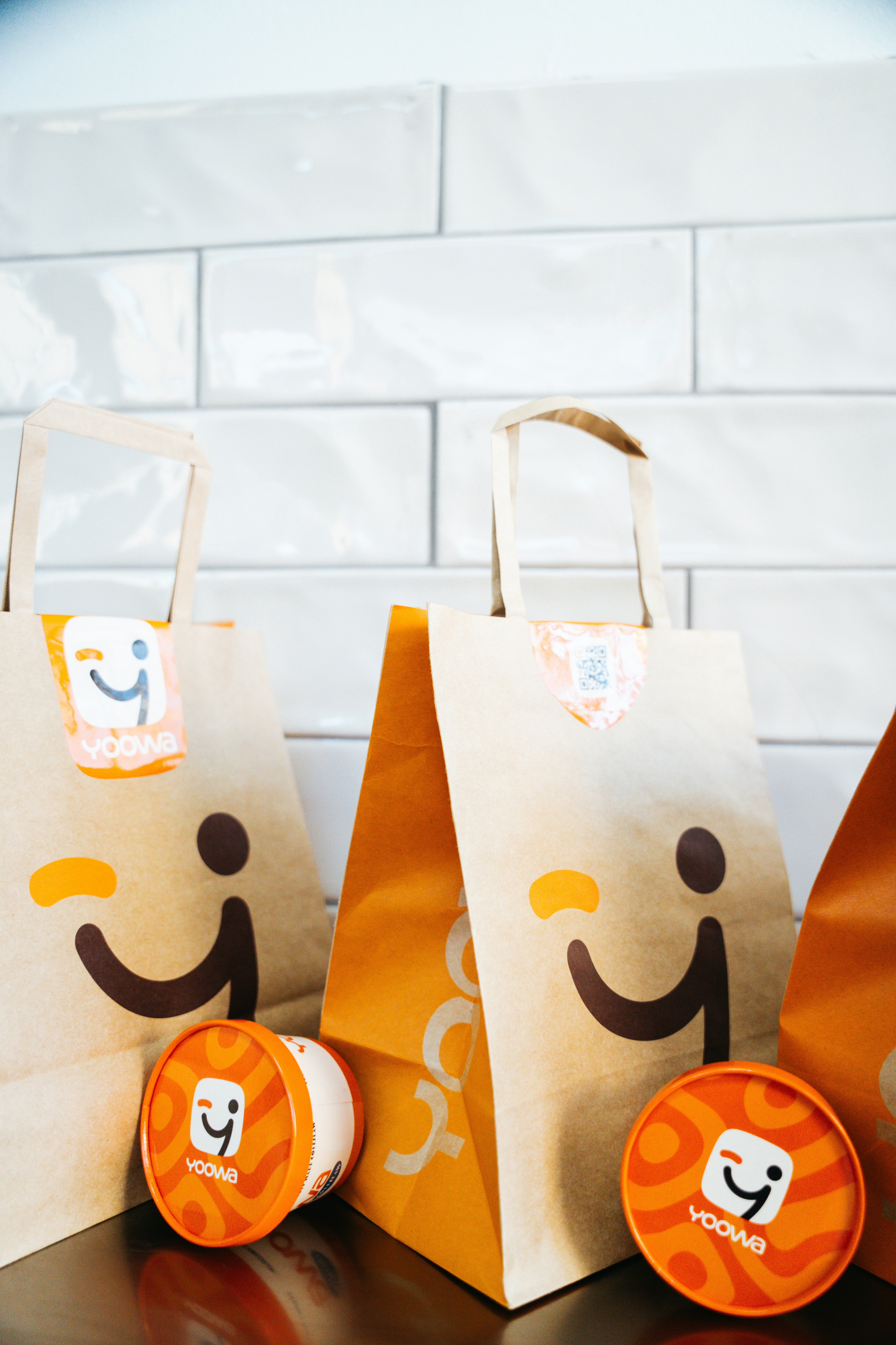 Brown paper bags and small containers with a smiling logo.