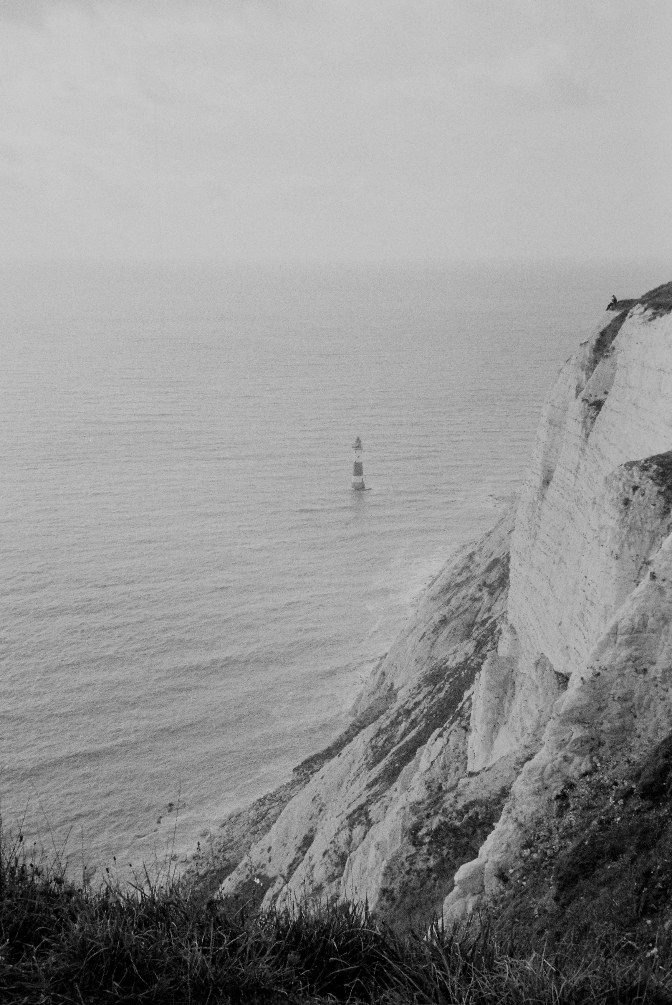 Faro nel mare accanto a imponenti scogliere bianche.