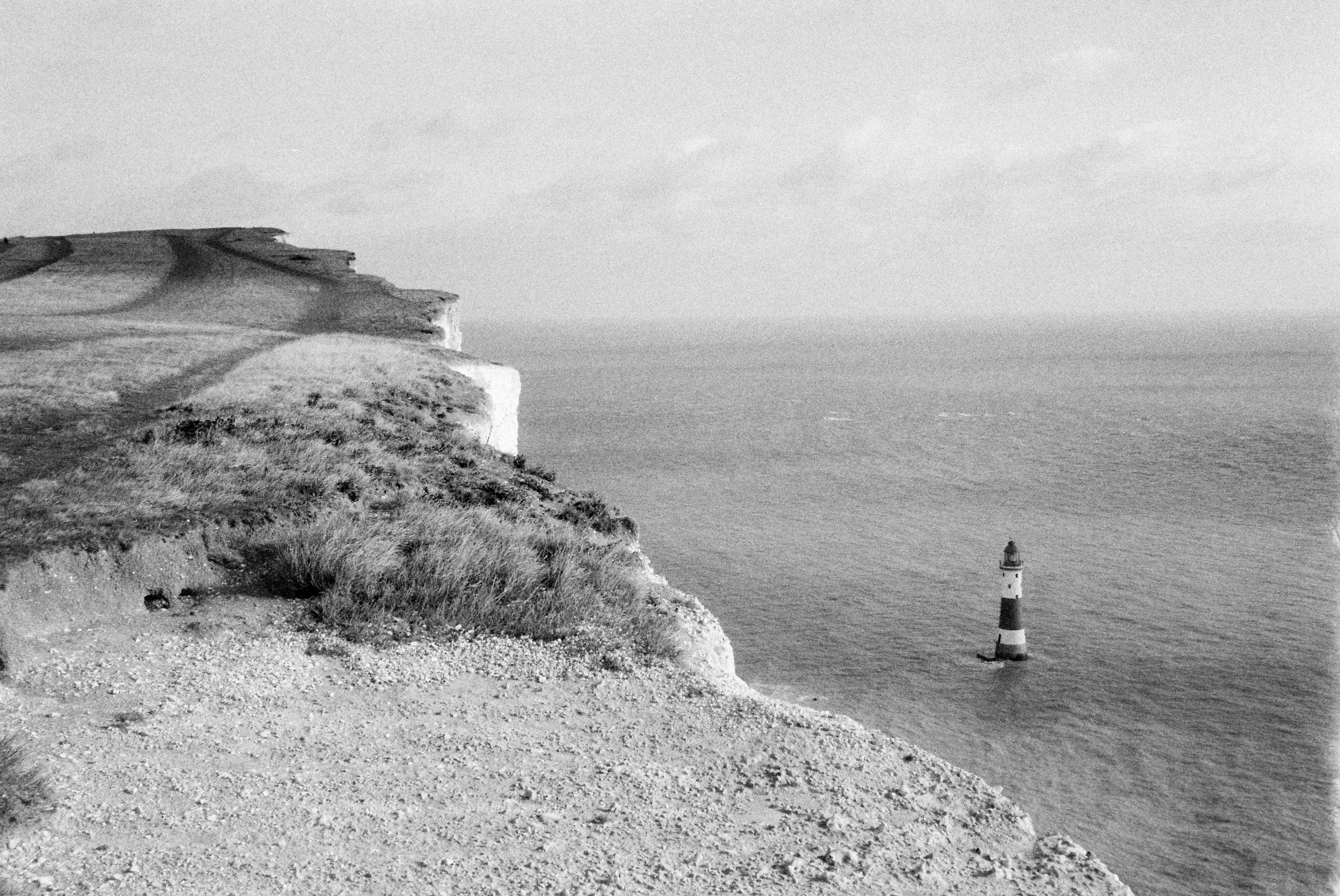 Scogliera bianca e nera e faro sul mare.