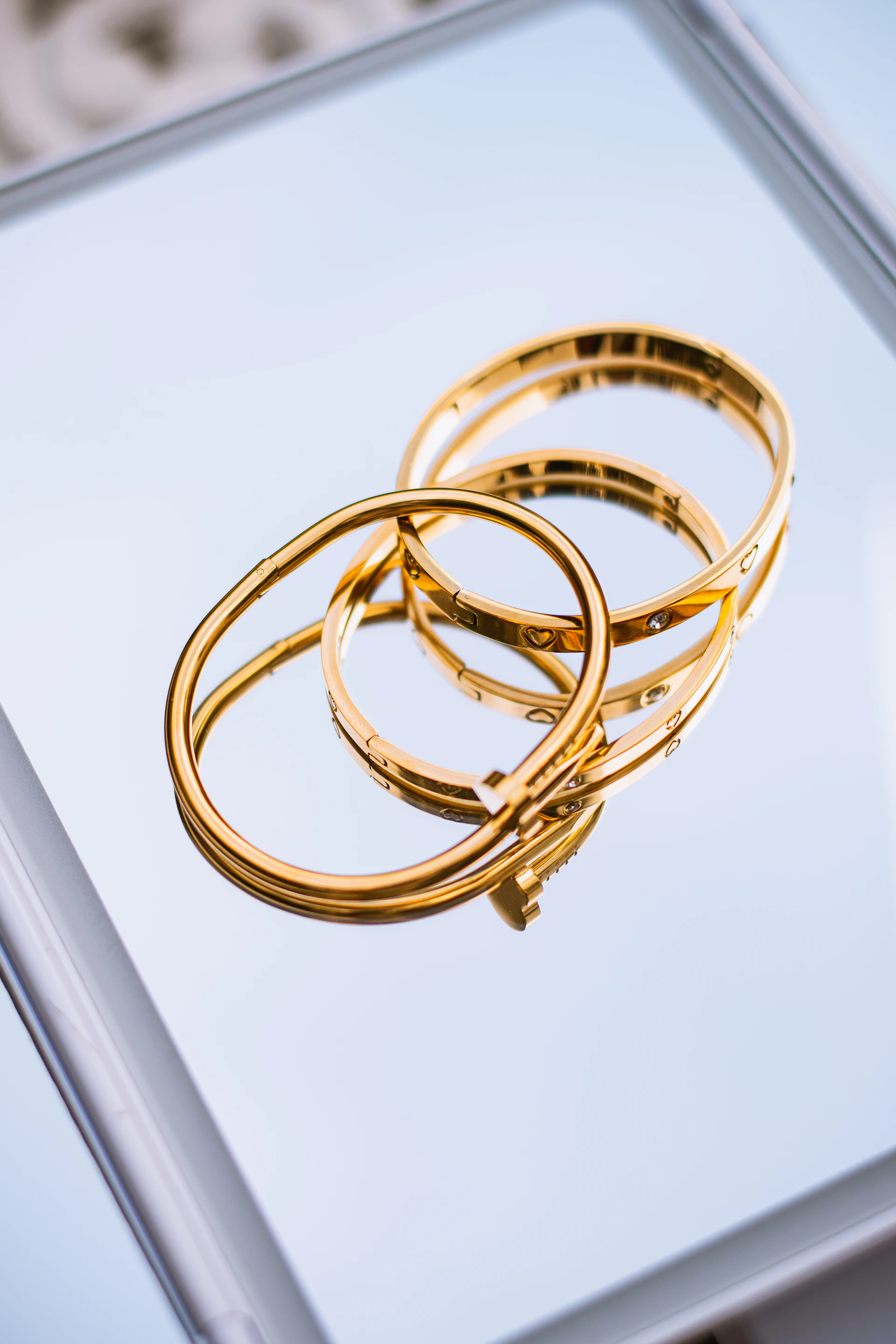 Two golden bracelets on a reflective mirror