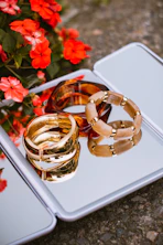 Assorted bracelets on a mirror reflecting red flowers