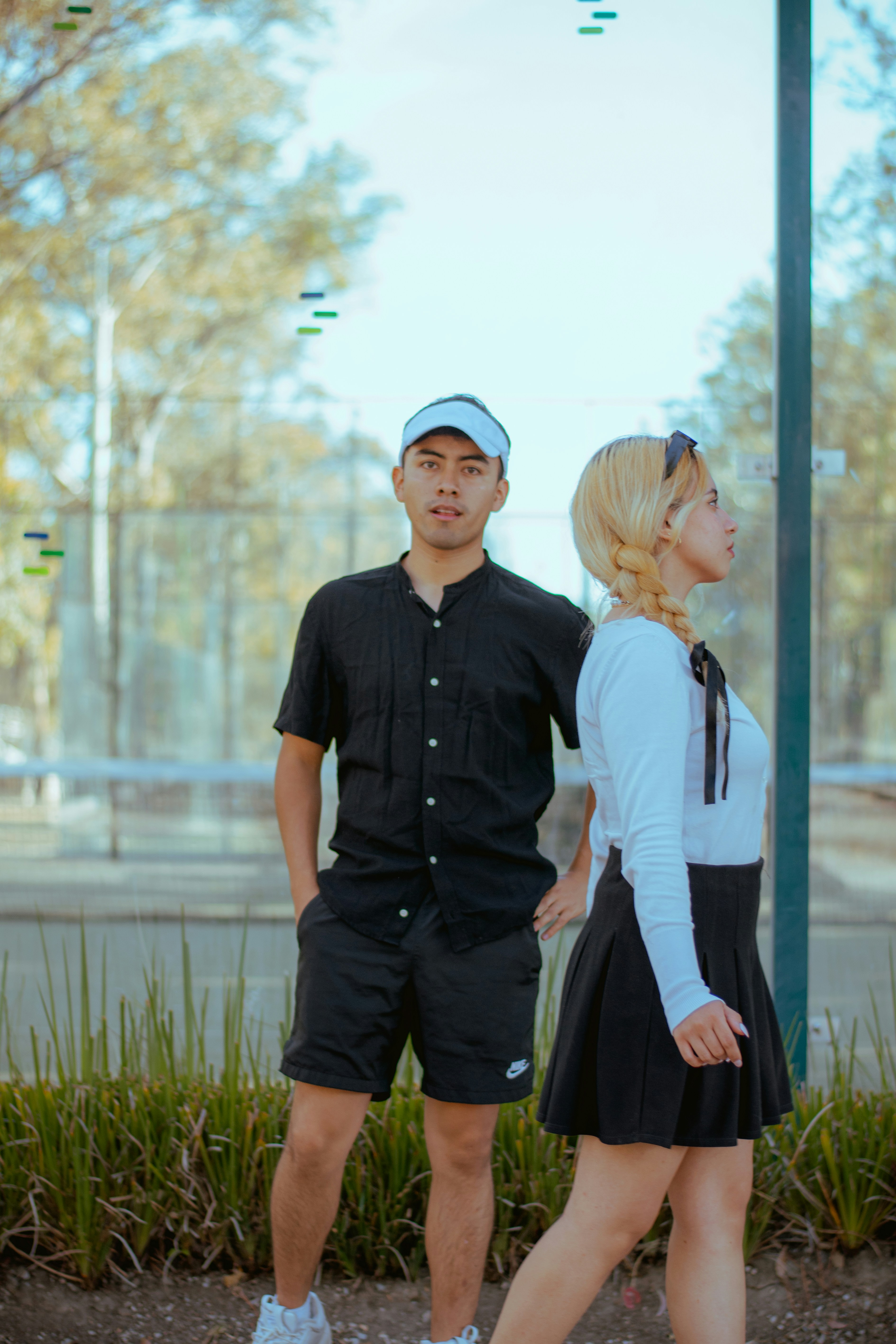 Two young people standing by a tennis court
