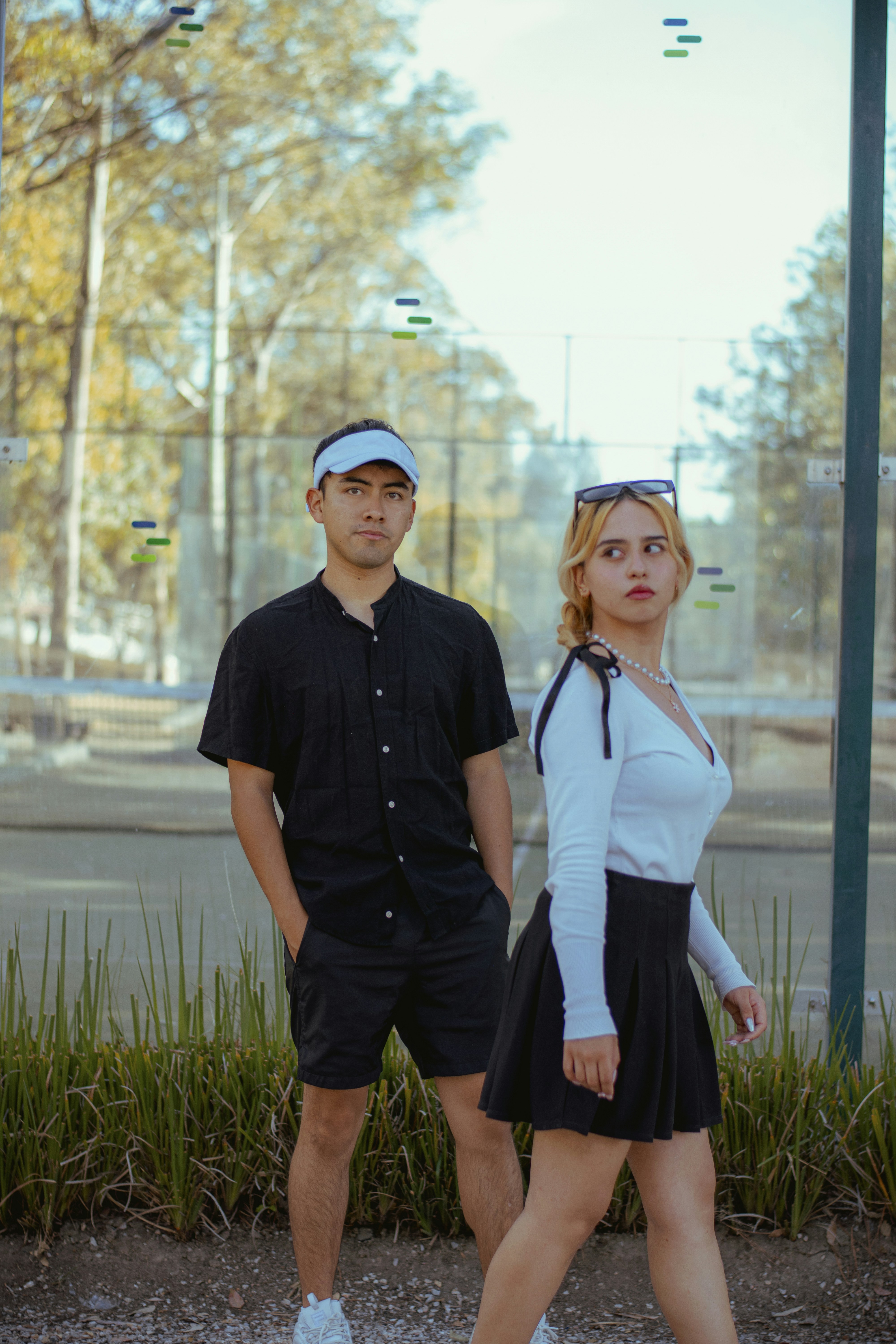 Young man and woman standing outdoors near a tennis court
