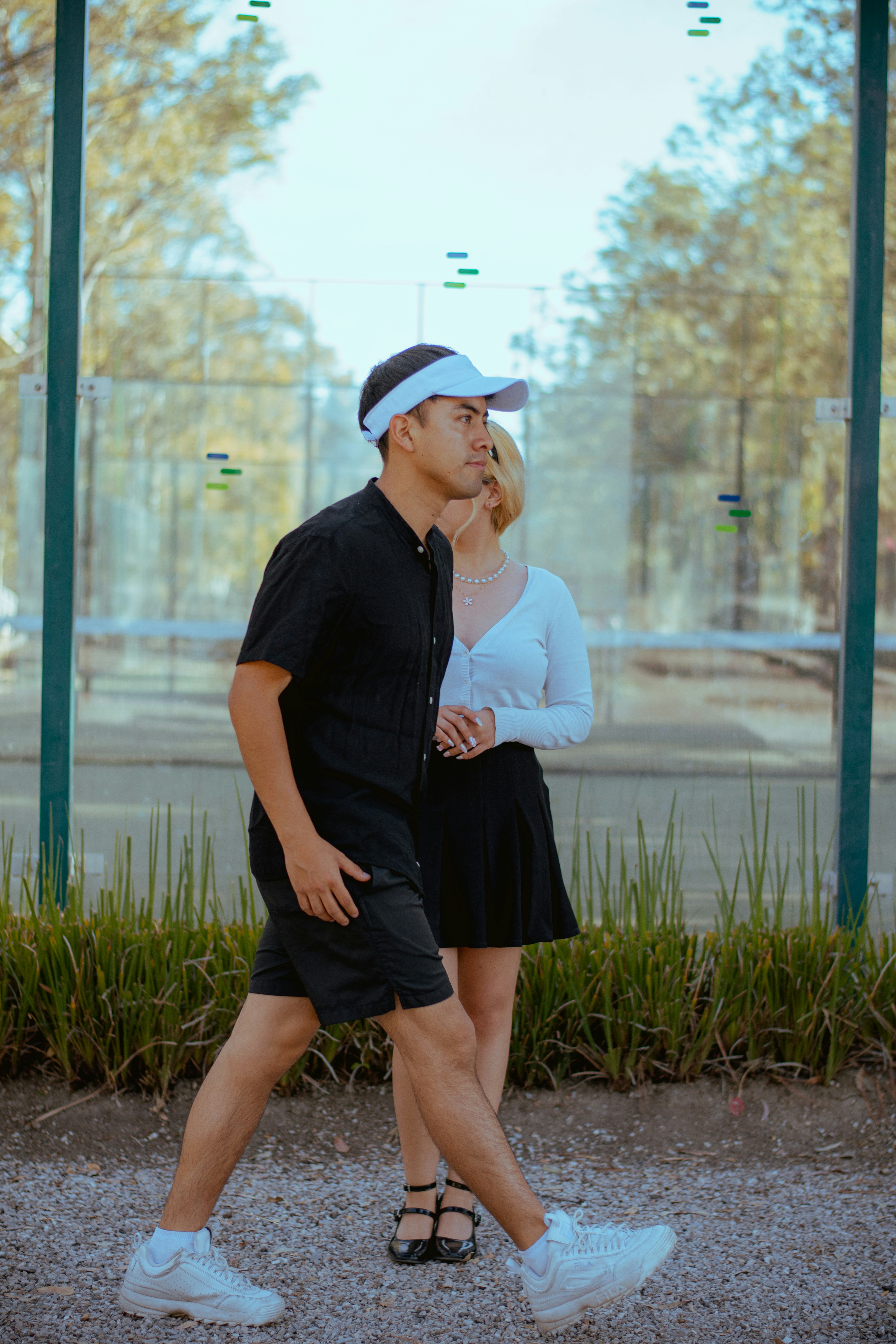 Man in black walks past woman on outdoor court