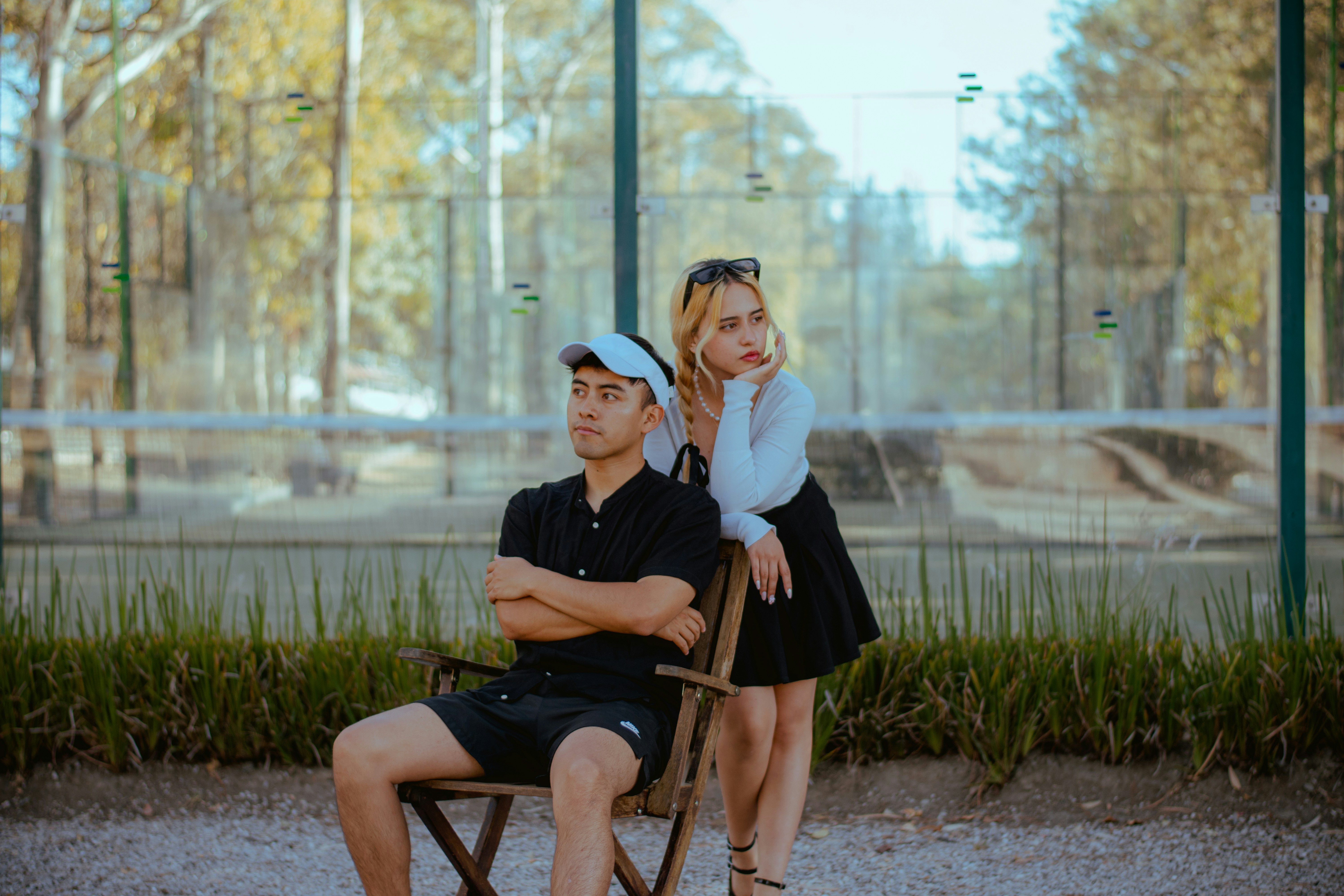 Man and woman posing outdoors near a sports court