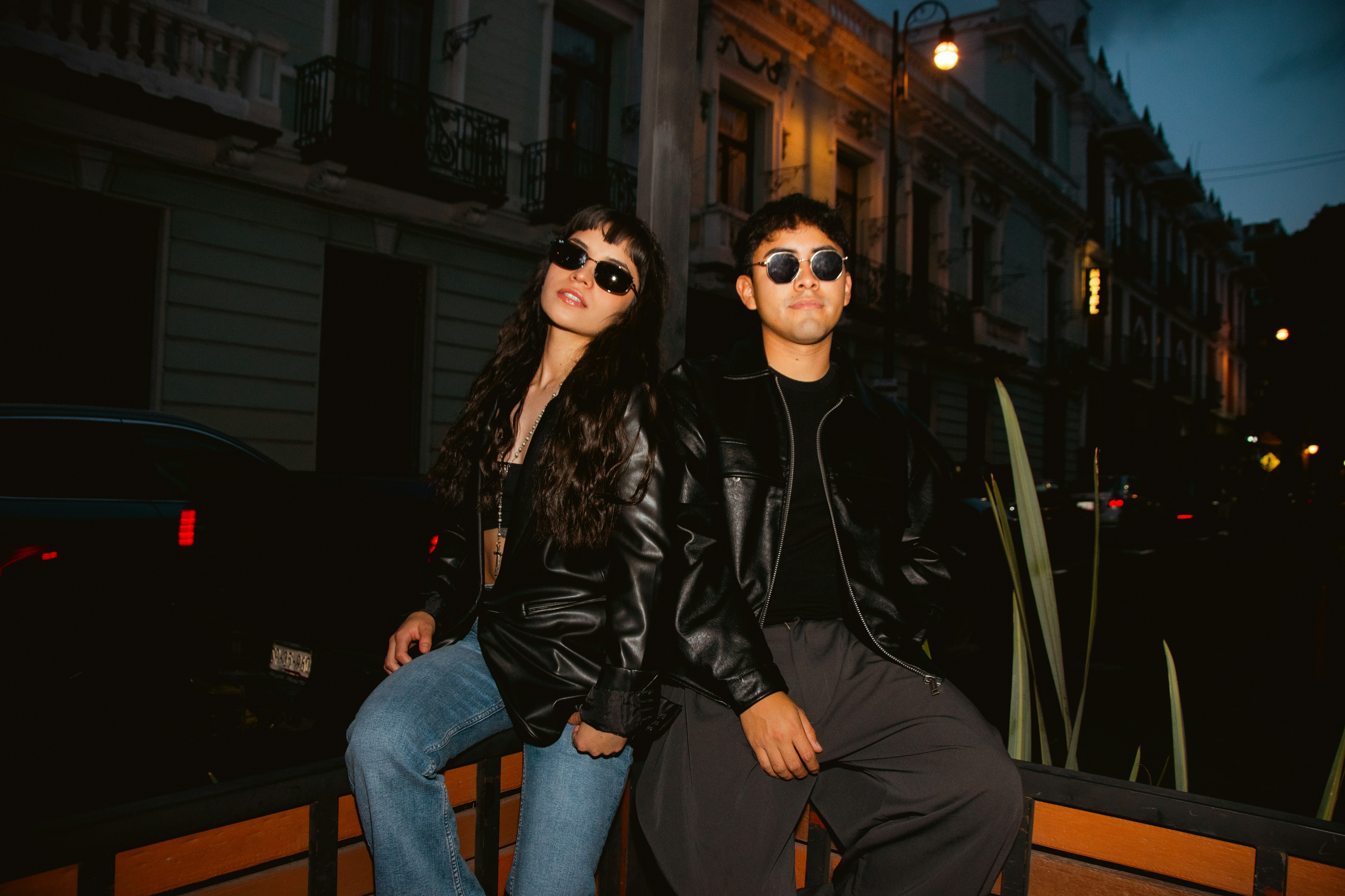 Two people wearing sunglasses and leather jackets at night