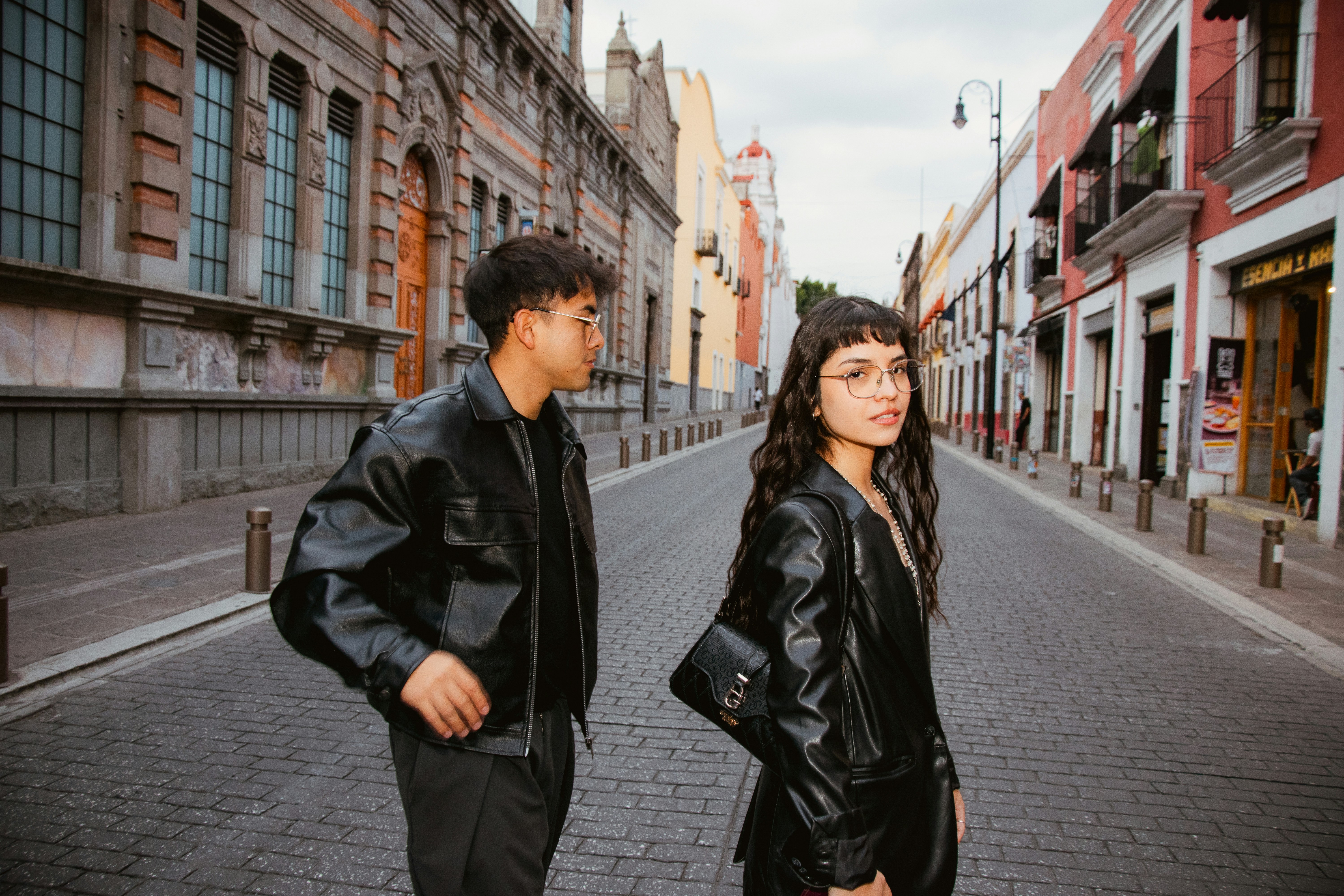 Young man and woman in leather jackets on city street