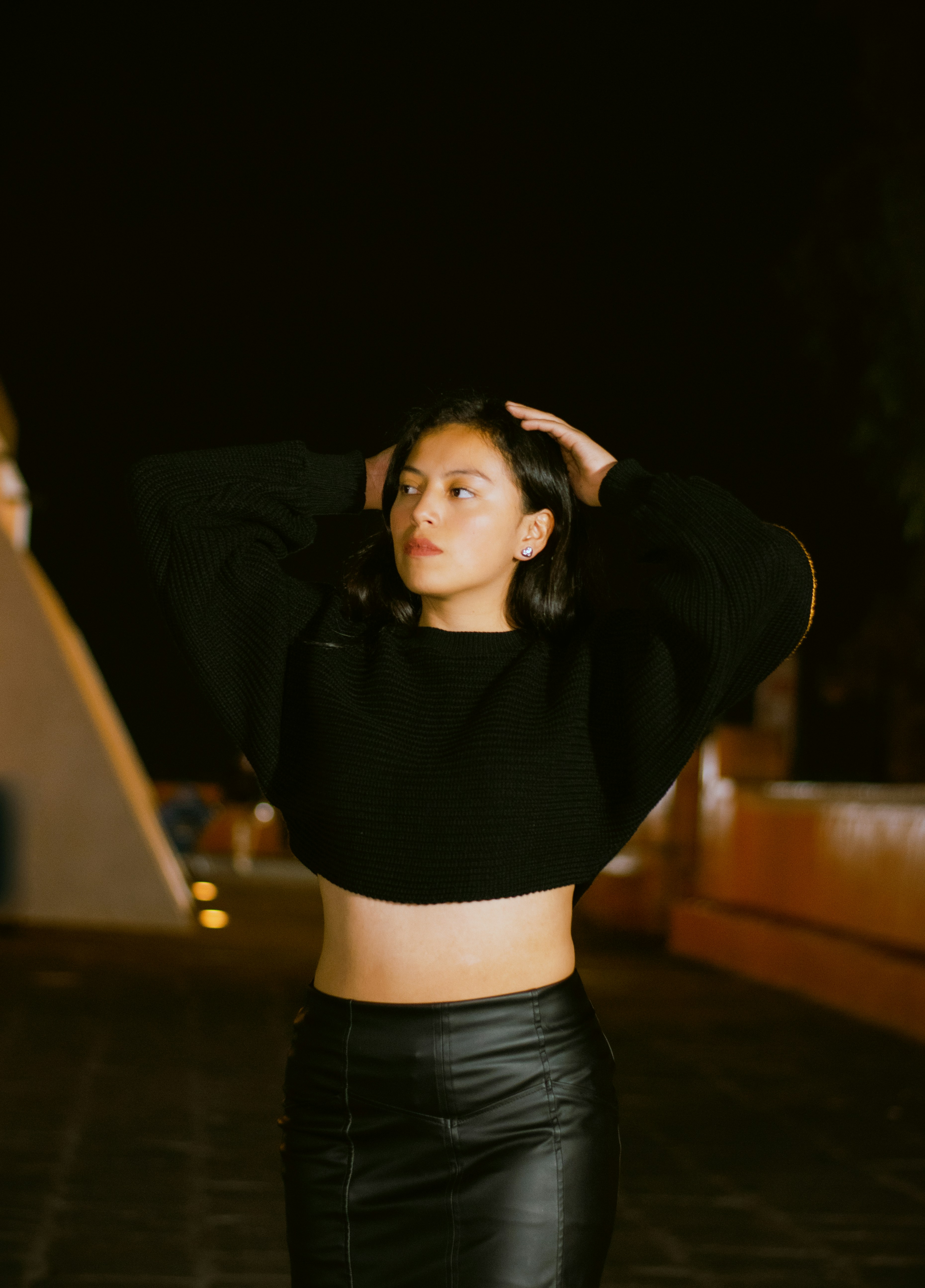 Wanita muda dengan crop top hitam dan rok di malam hari