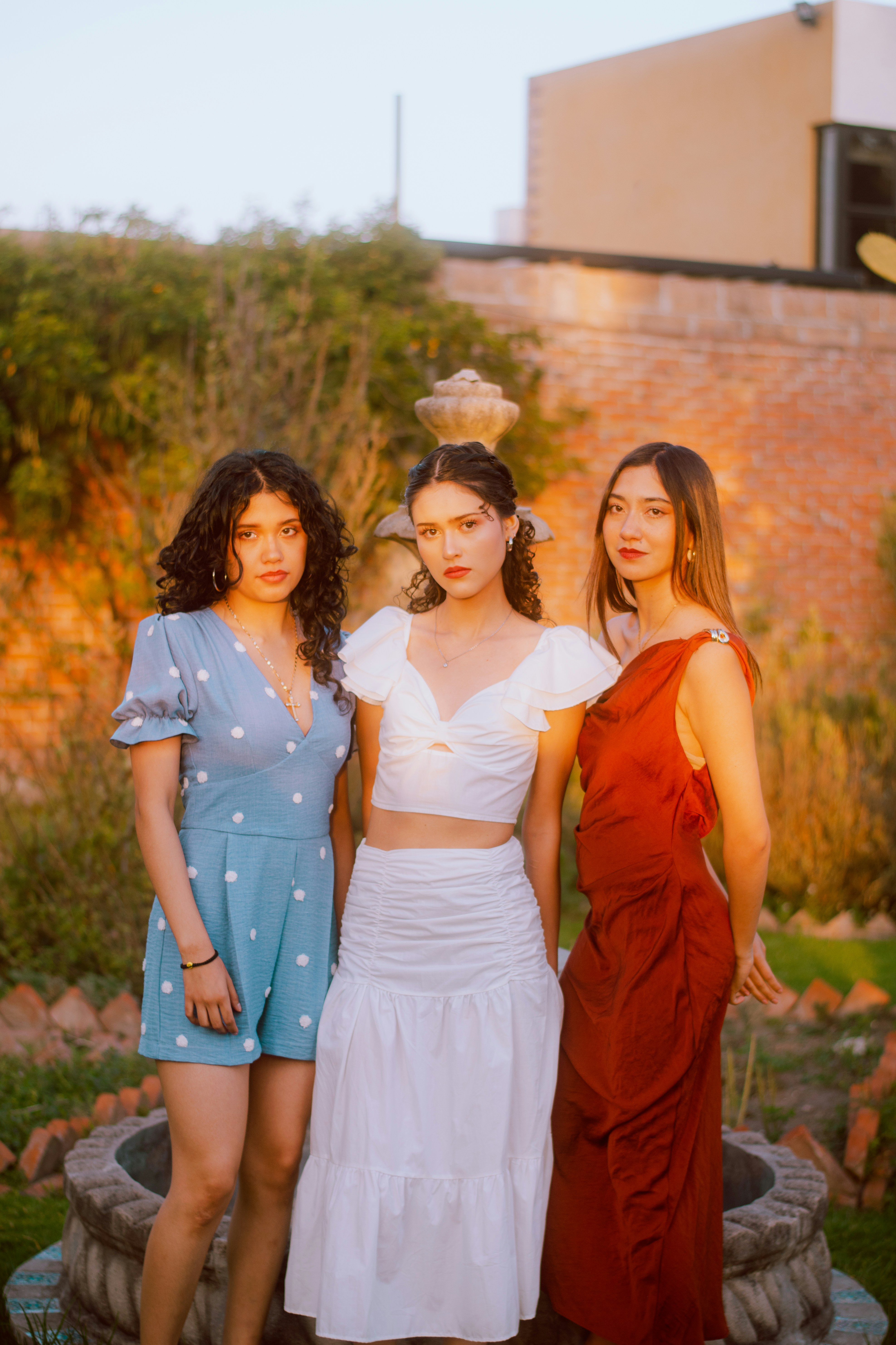 Three young women posing outdoors at sunset