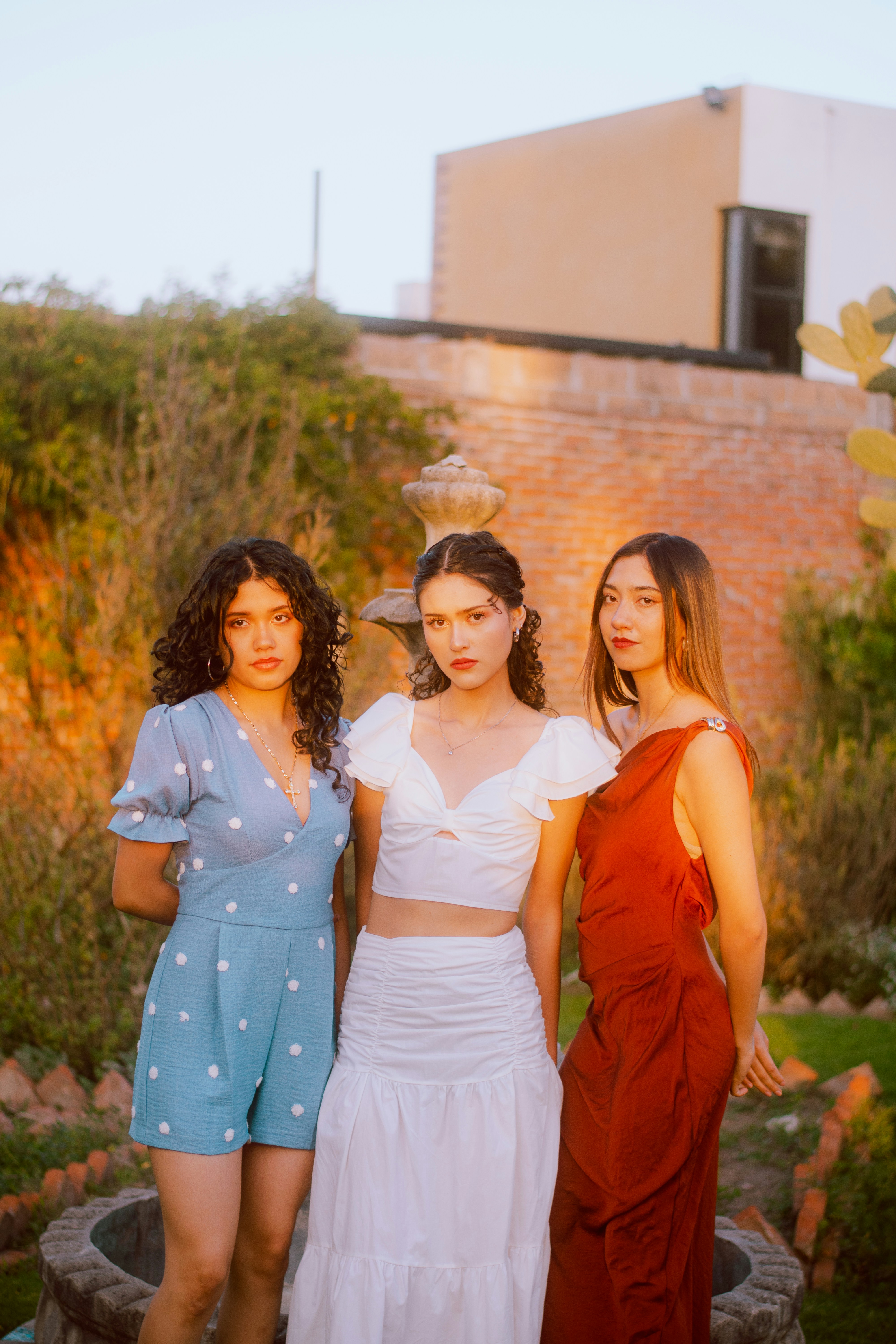 Three young women standing in a garden at sunset