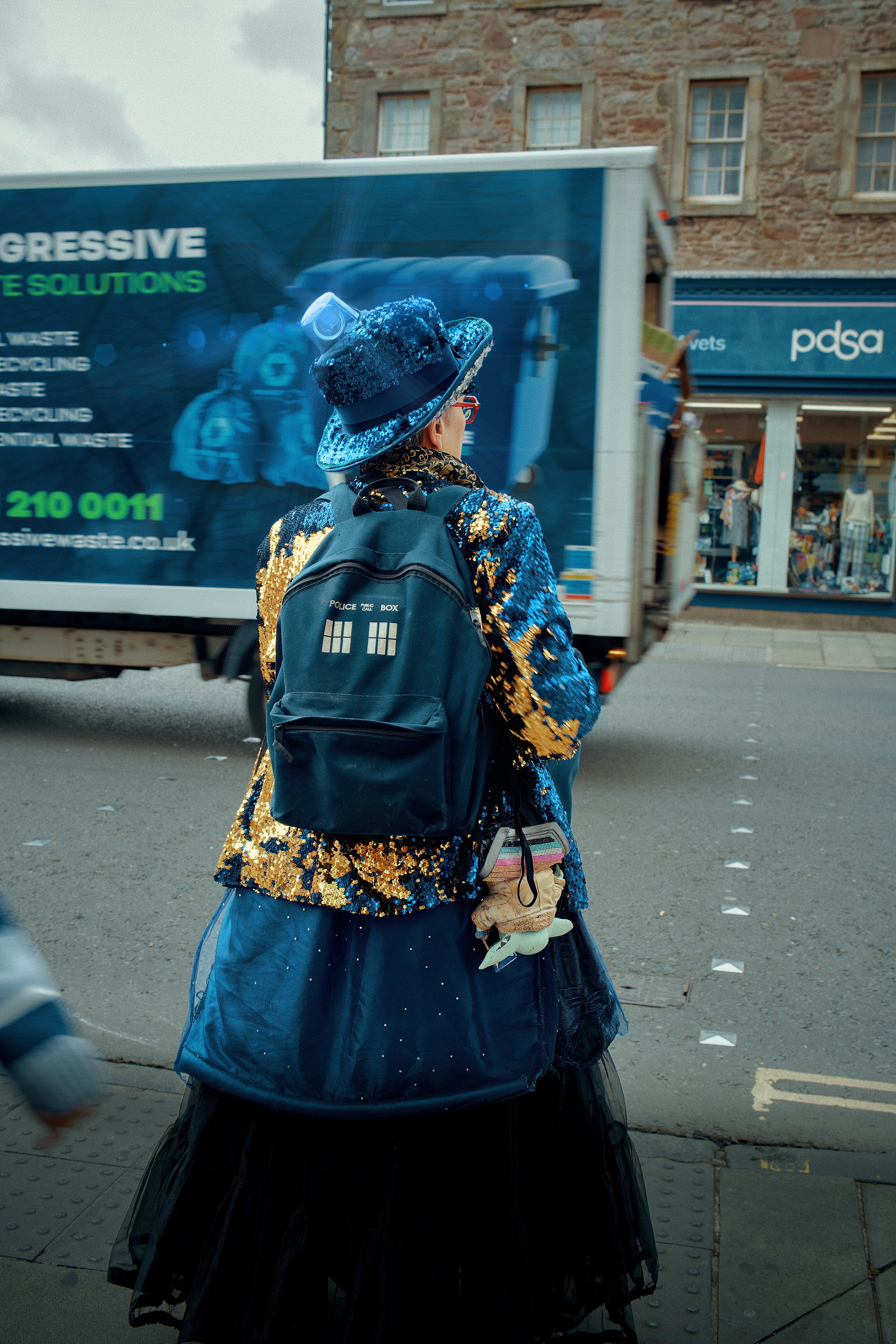 Person in sequined blue outfit with tardis backpack.