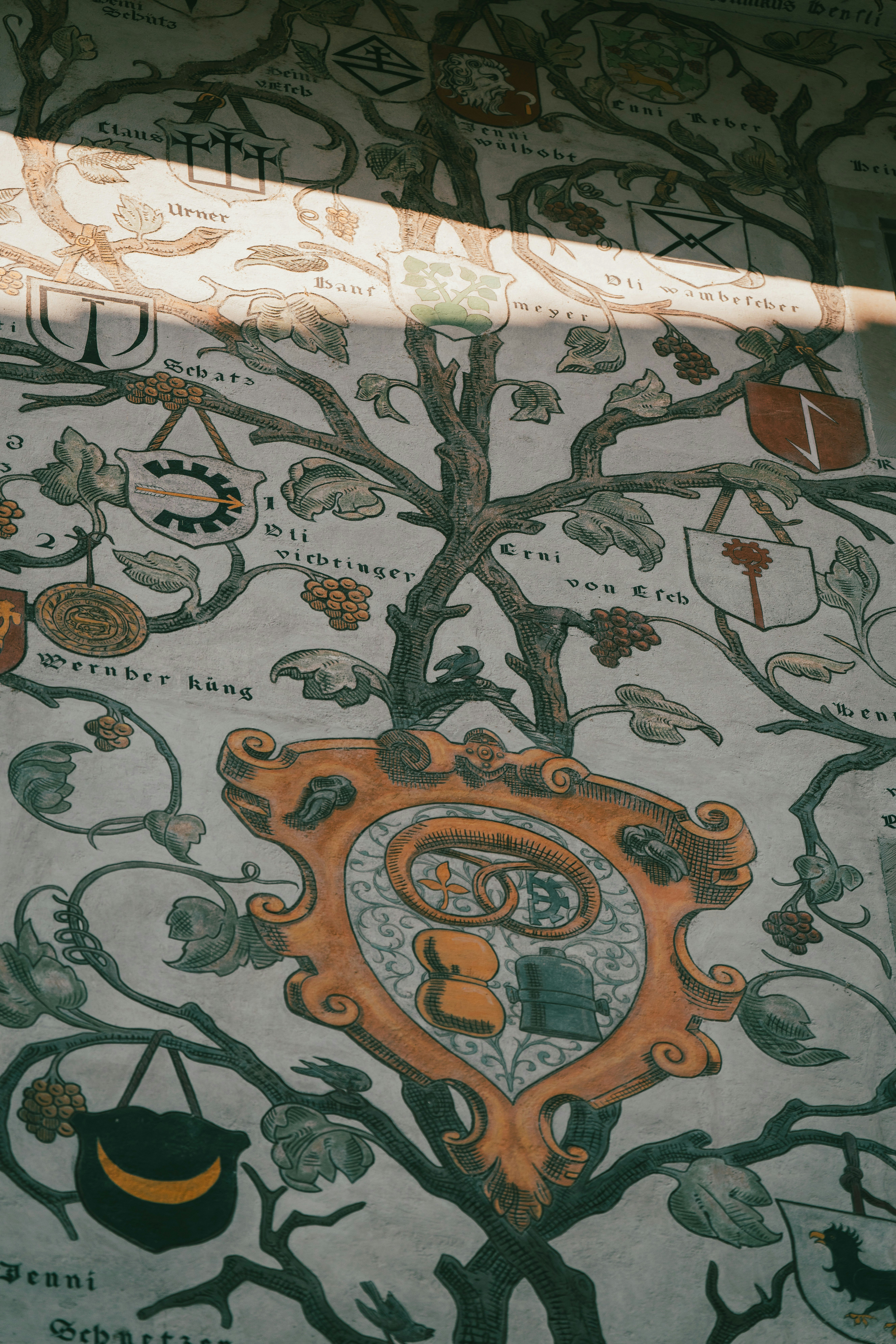 Ancient family tree mural with heraldry and sunlight