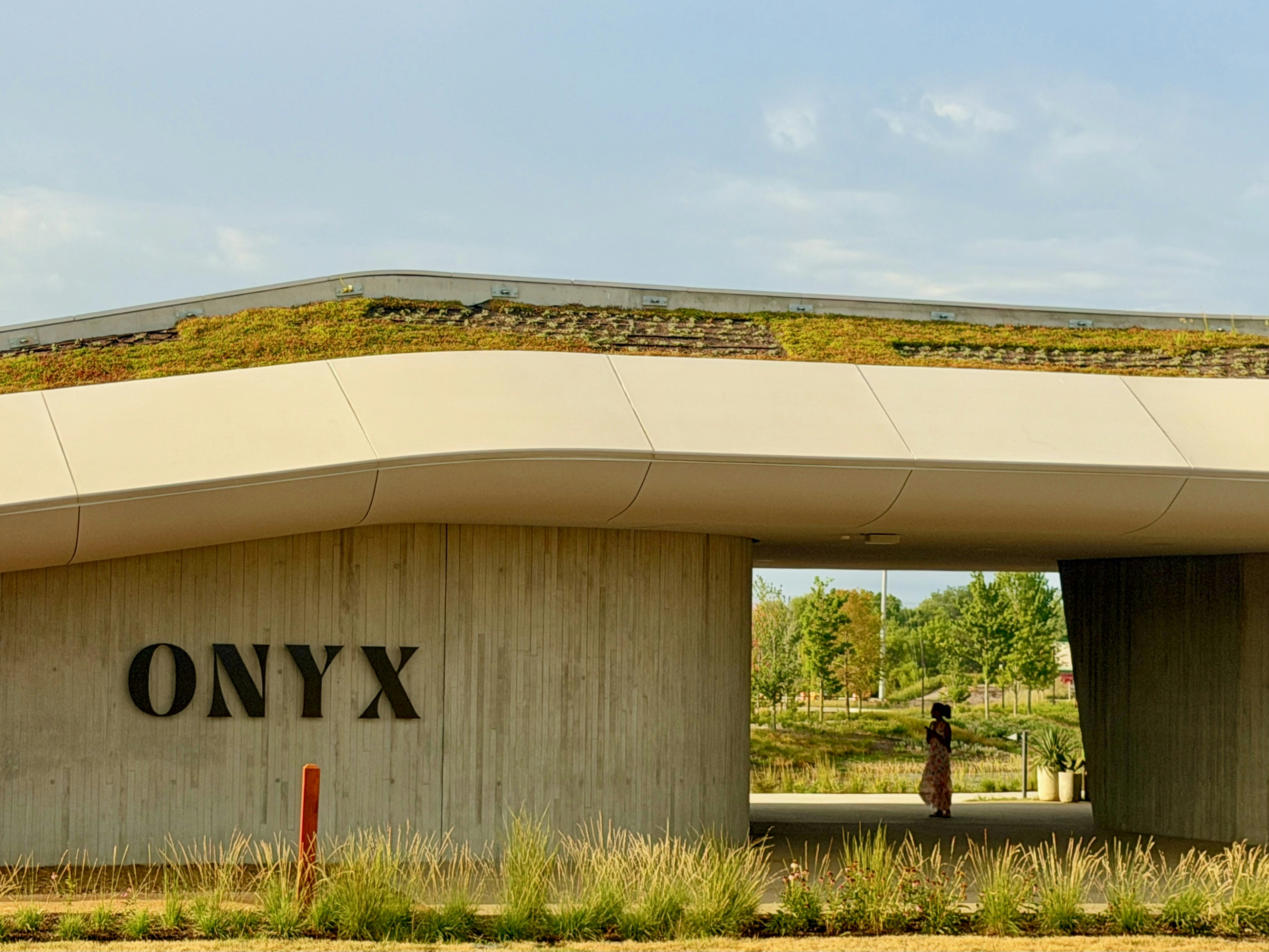 Onyx building with green roof and person walking through archway