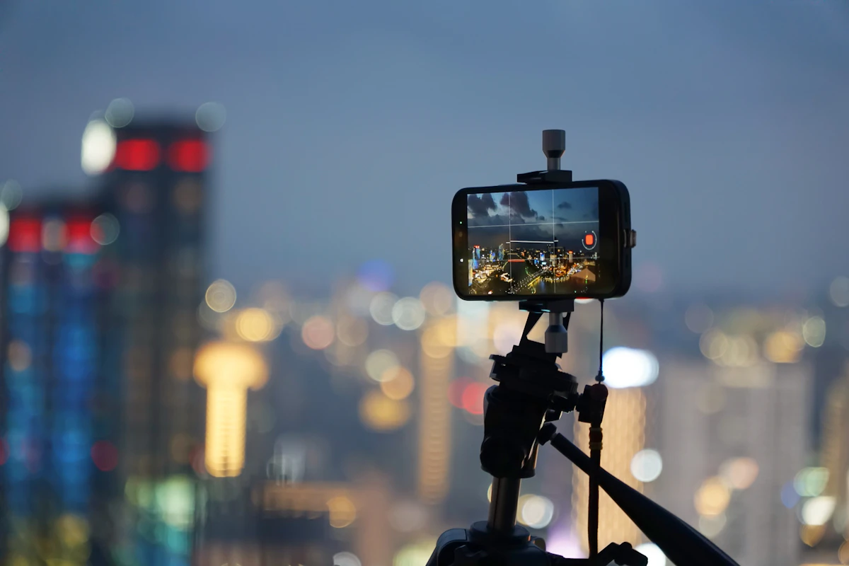 A phone on a tripod records a city skyline at night
