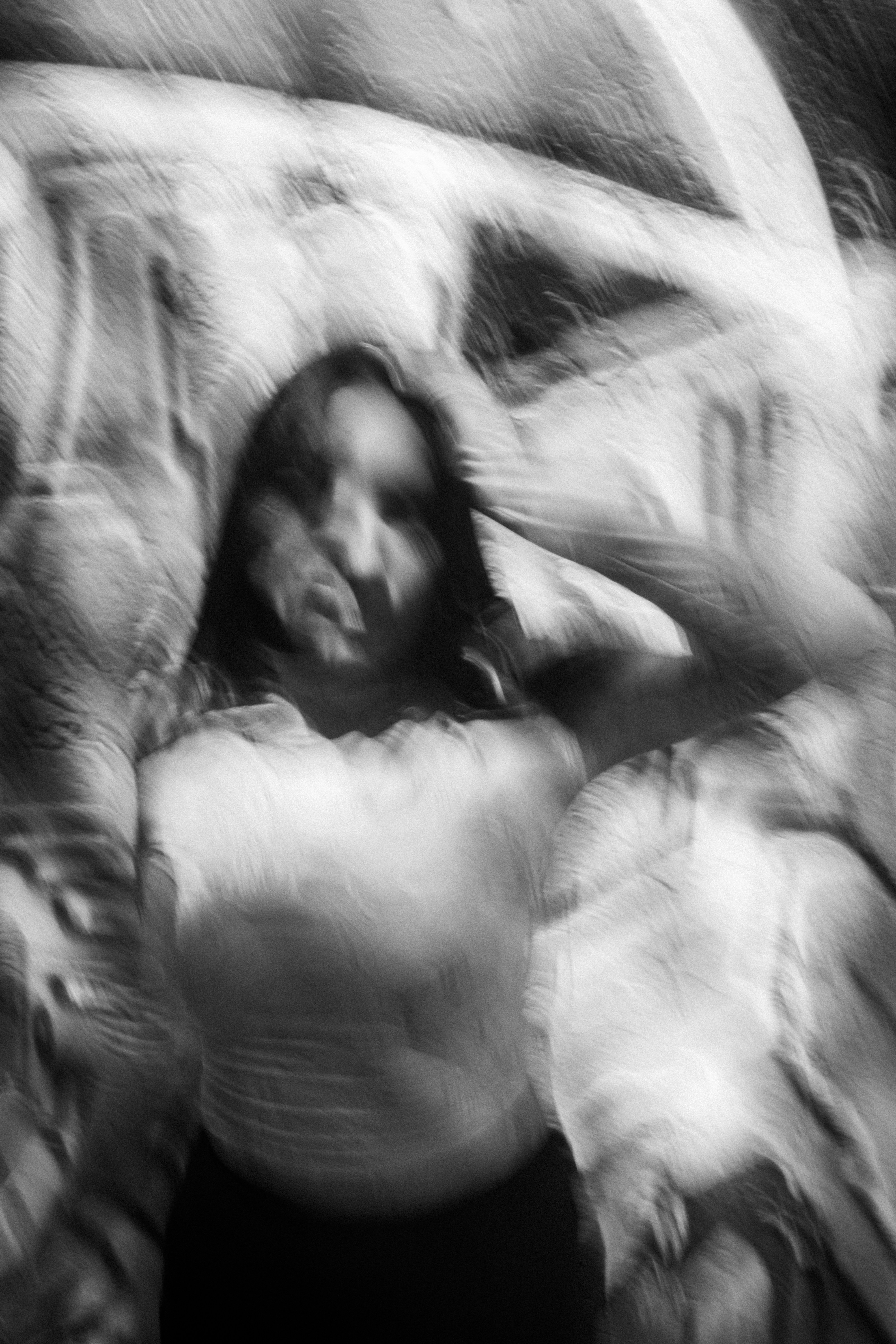 A person with long hair in a blurred black and white portrait