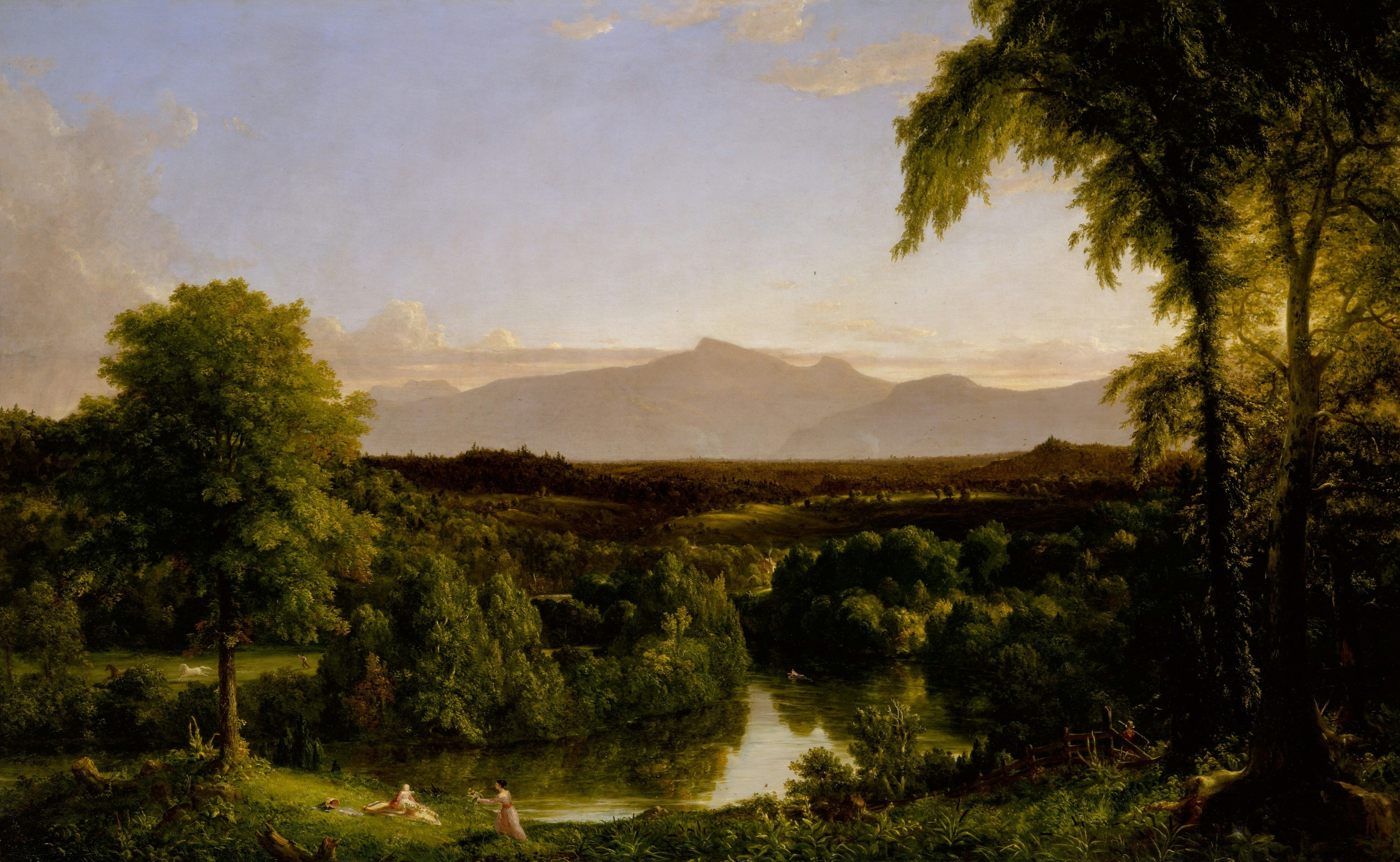 A river winding through a lush green valley beneath distant mountains at golden hour.