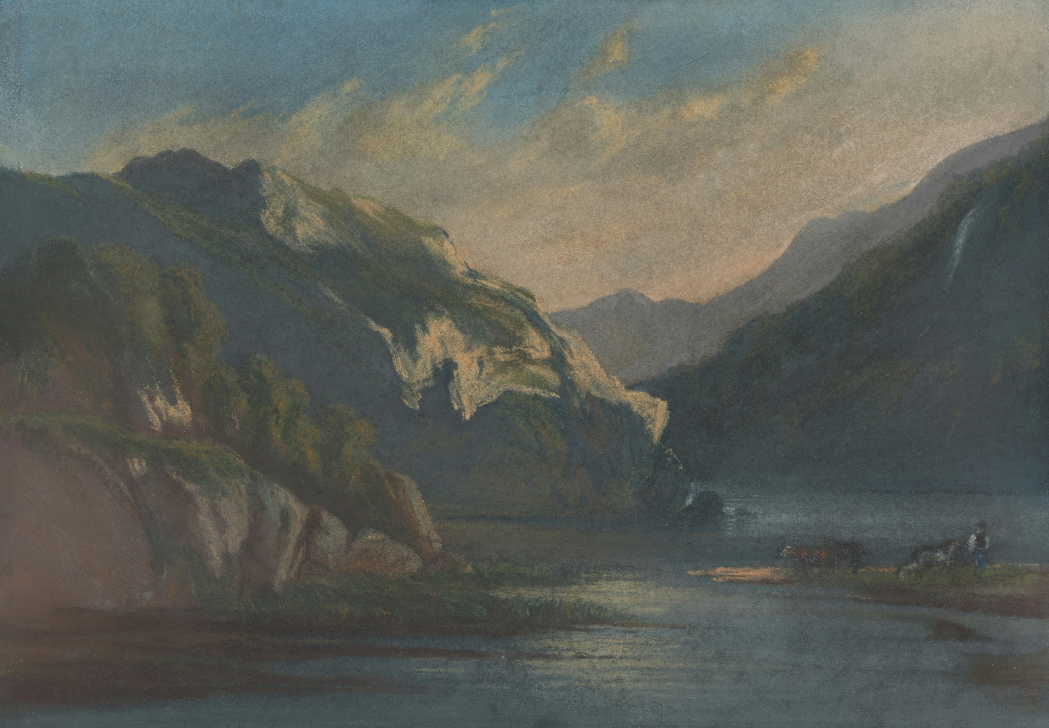 A person with cattle near a river flowing between steep, rocky mountains.