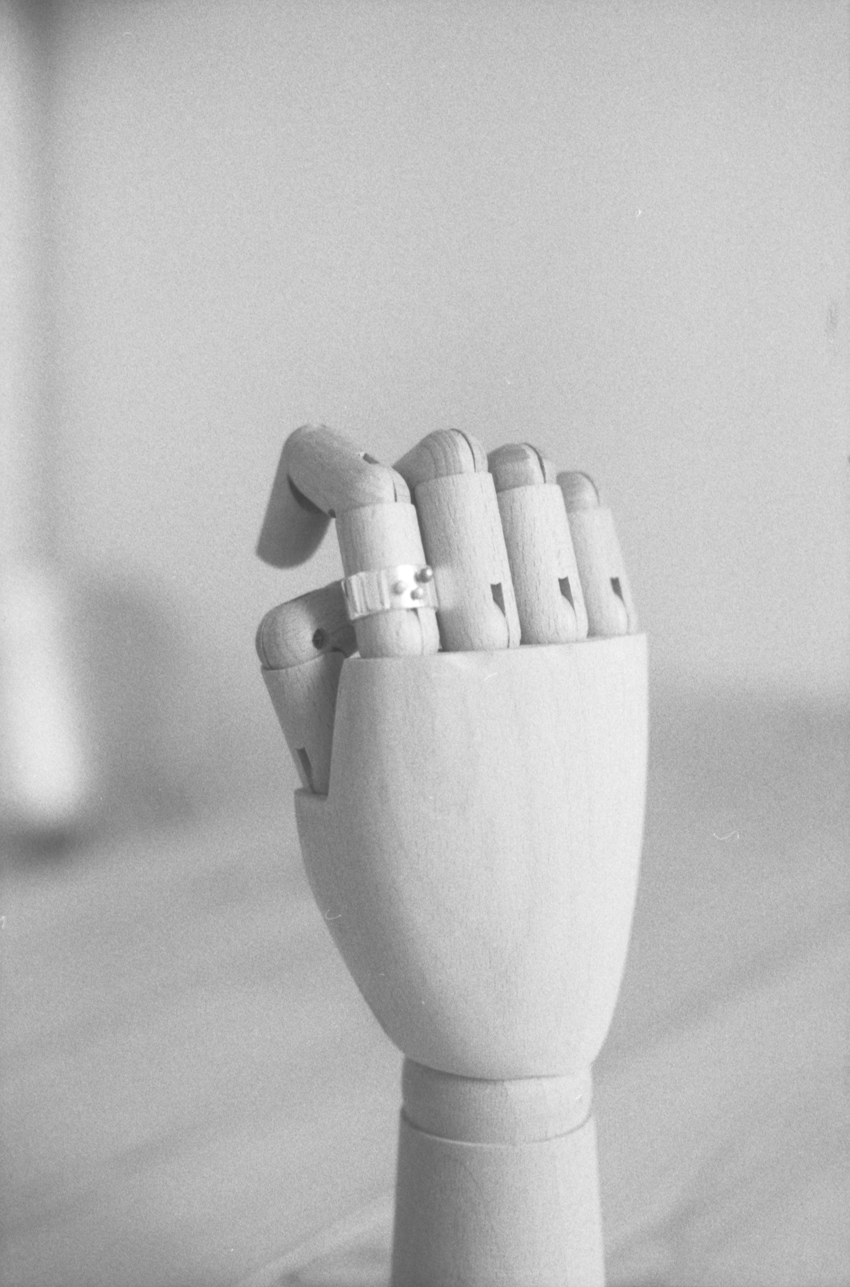 A wooden mannequin hand wearing a silver ring on a finger